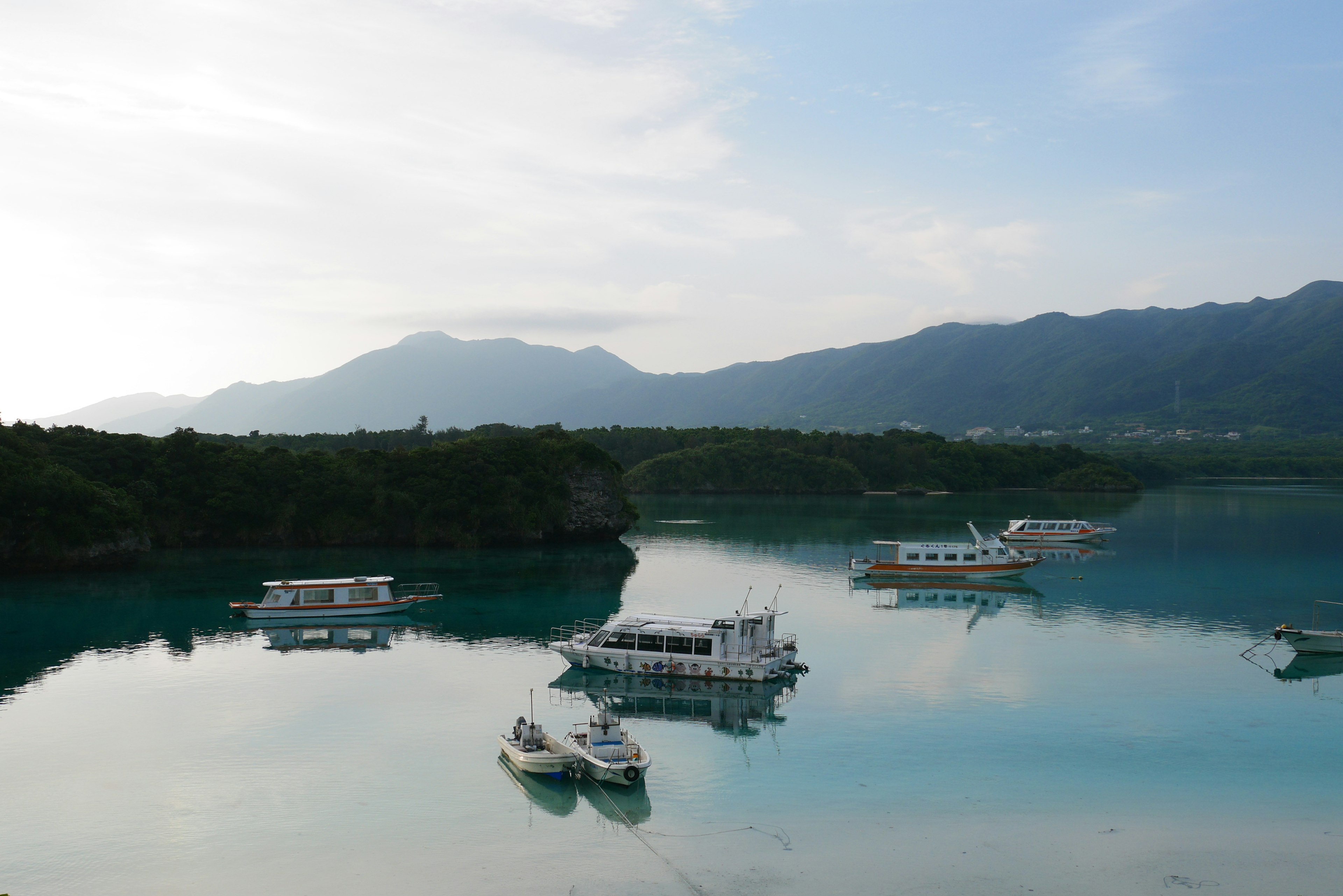 青い水面と山々を背景に浮かぶボート群