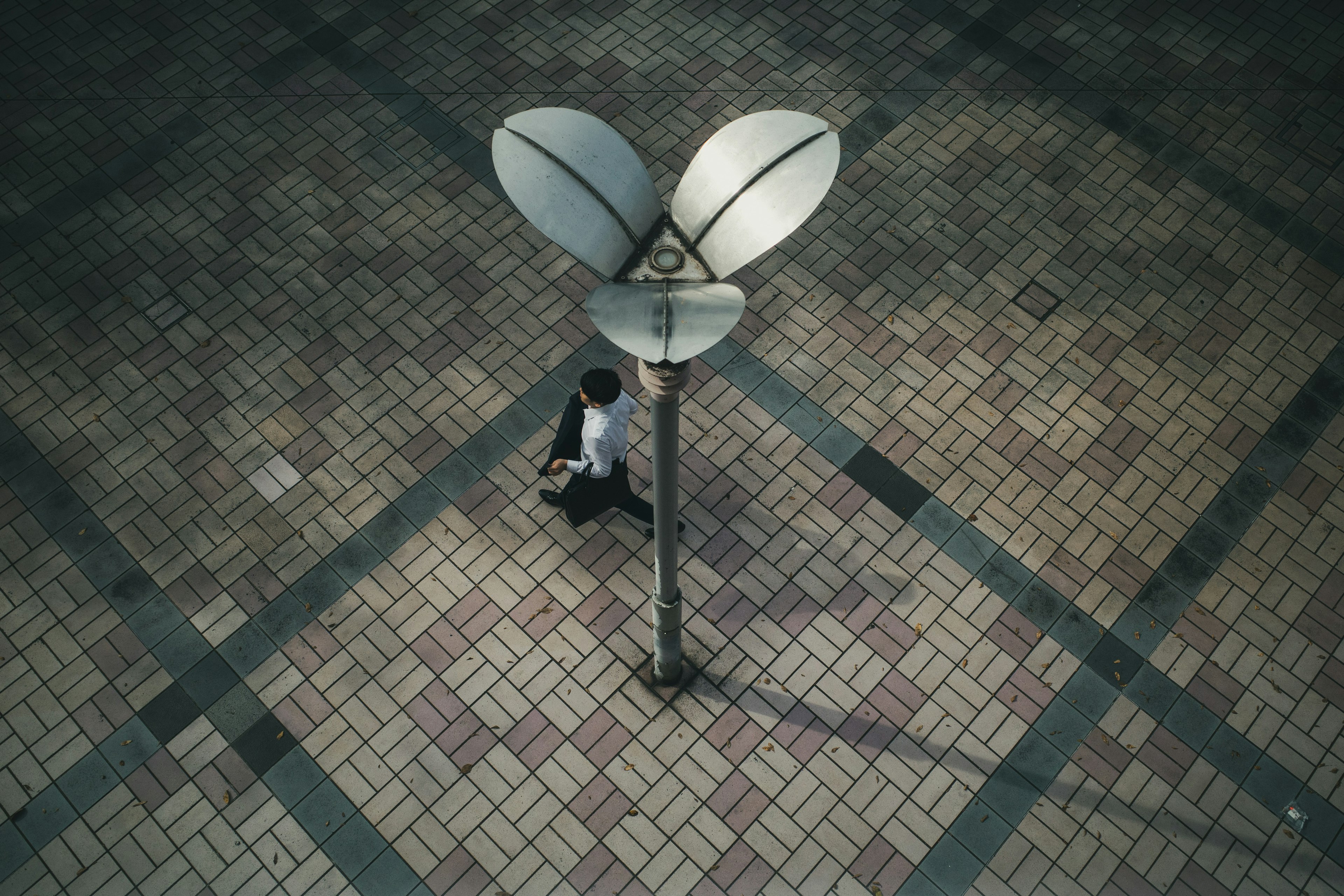 A man standing under a streetlight with a unique design on a tiled floor