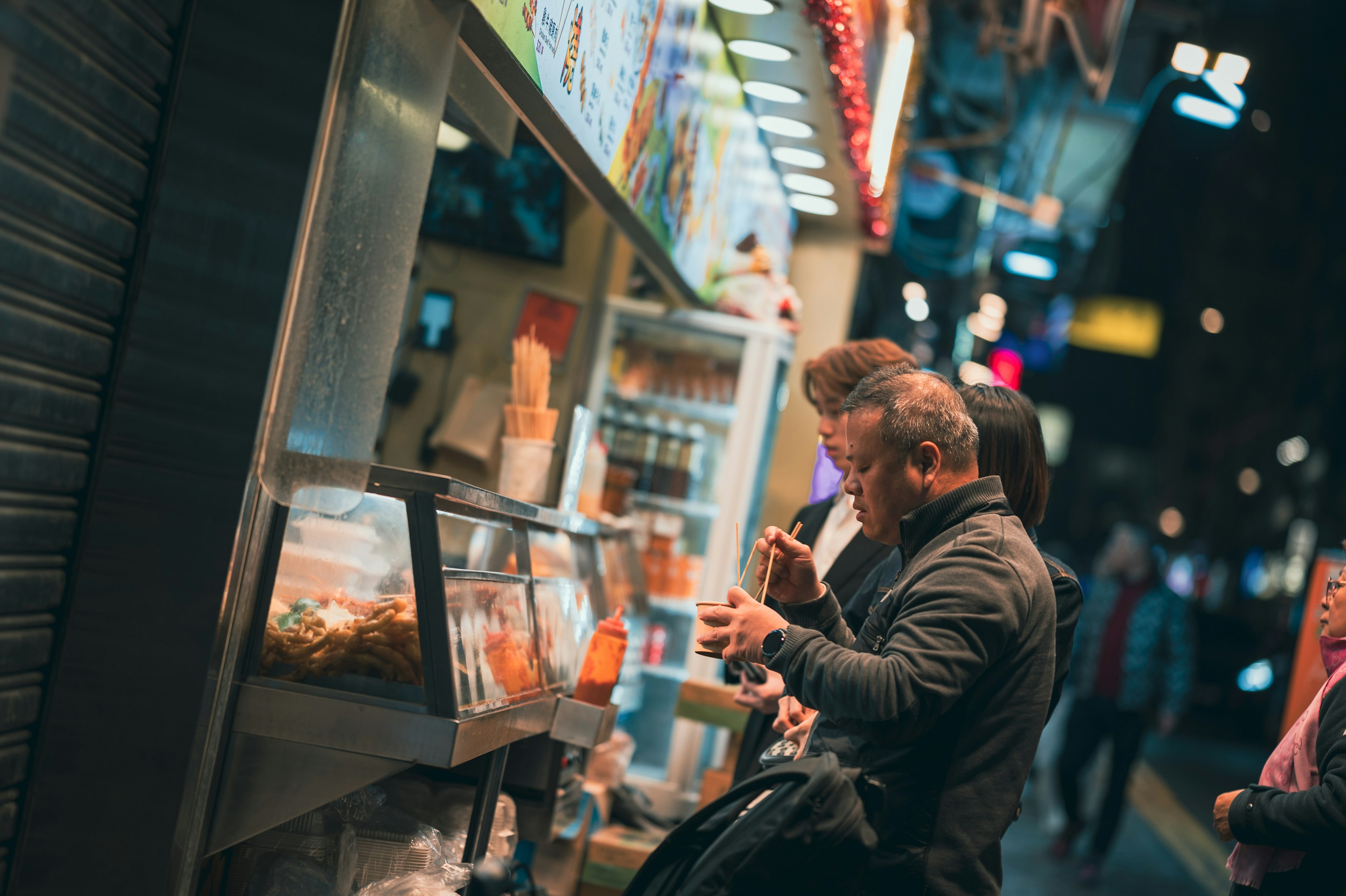 Personas pidiendo comida en un puesto callejero por la noche