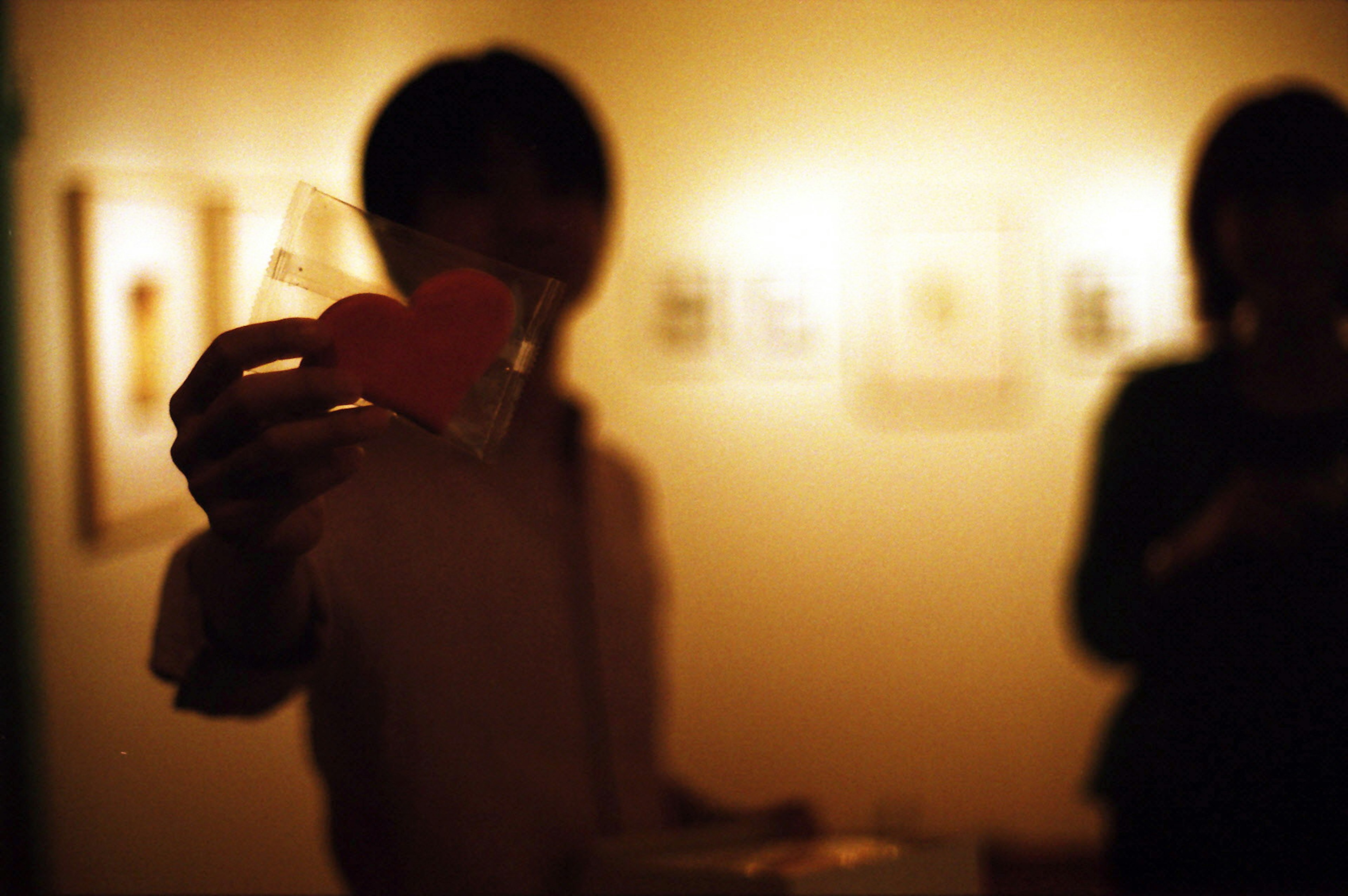 A person holding a heart-shaped object in a dimly lit background