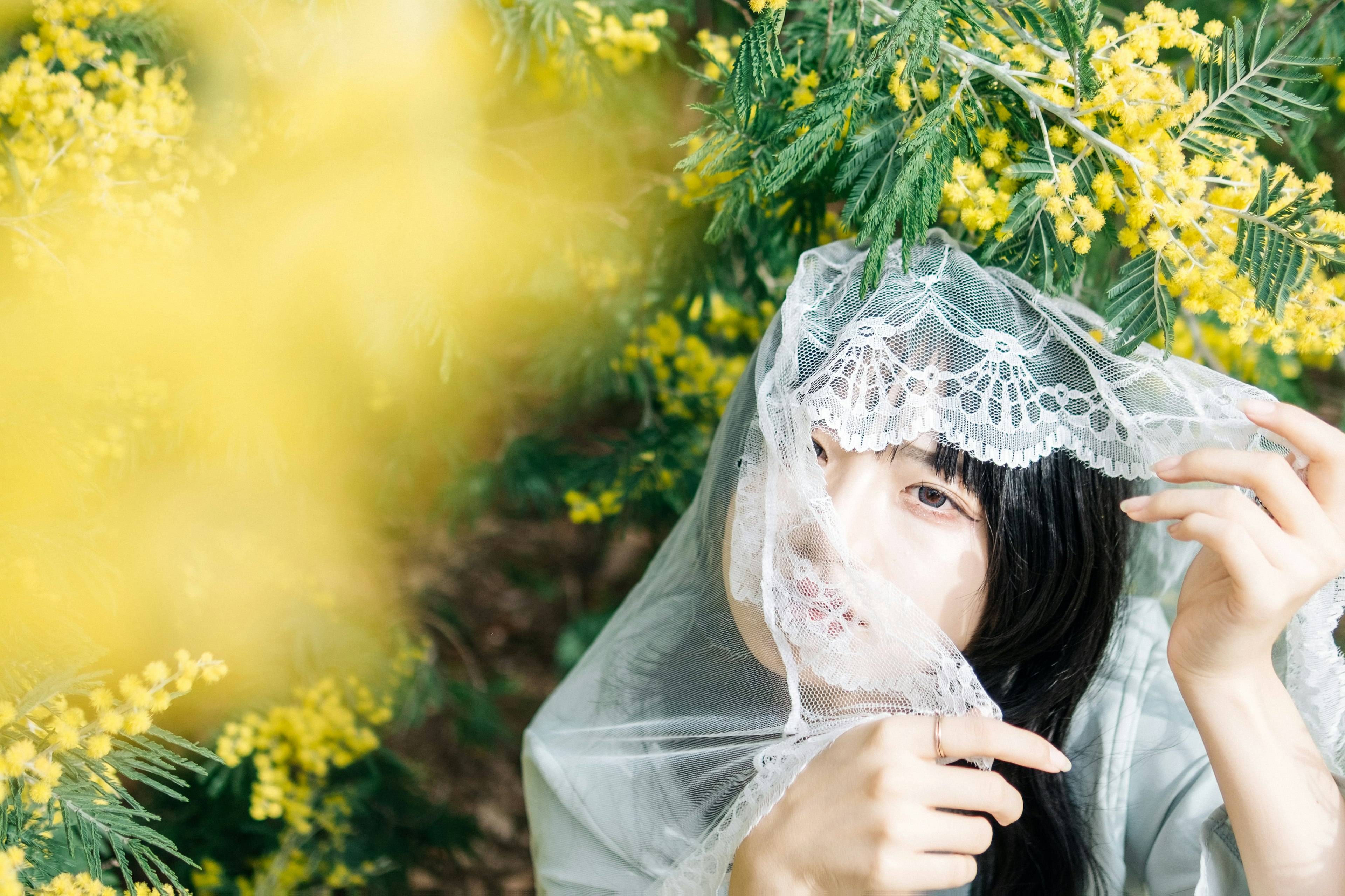 被黃色花朵環繞的女性手持蕾絲面紗