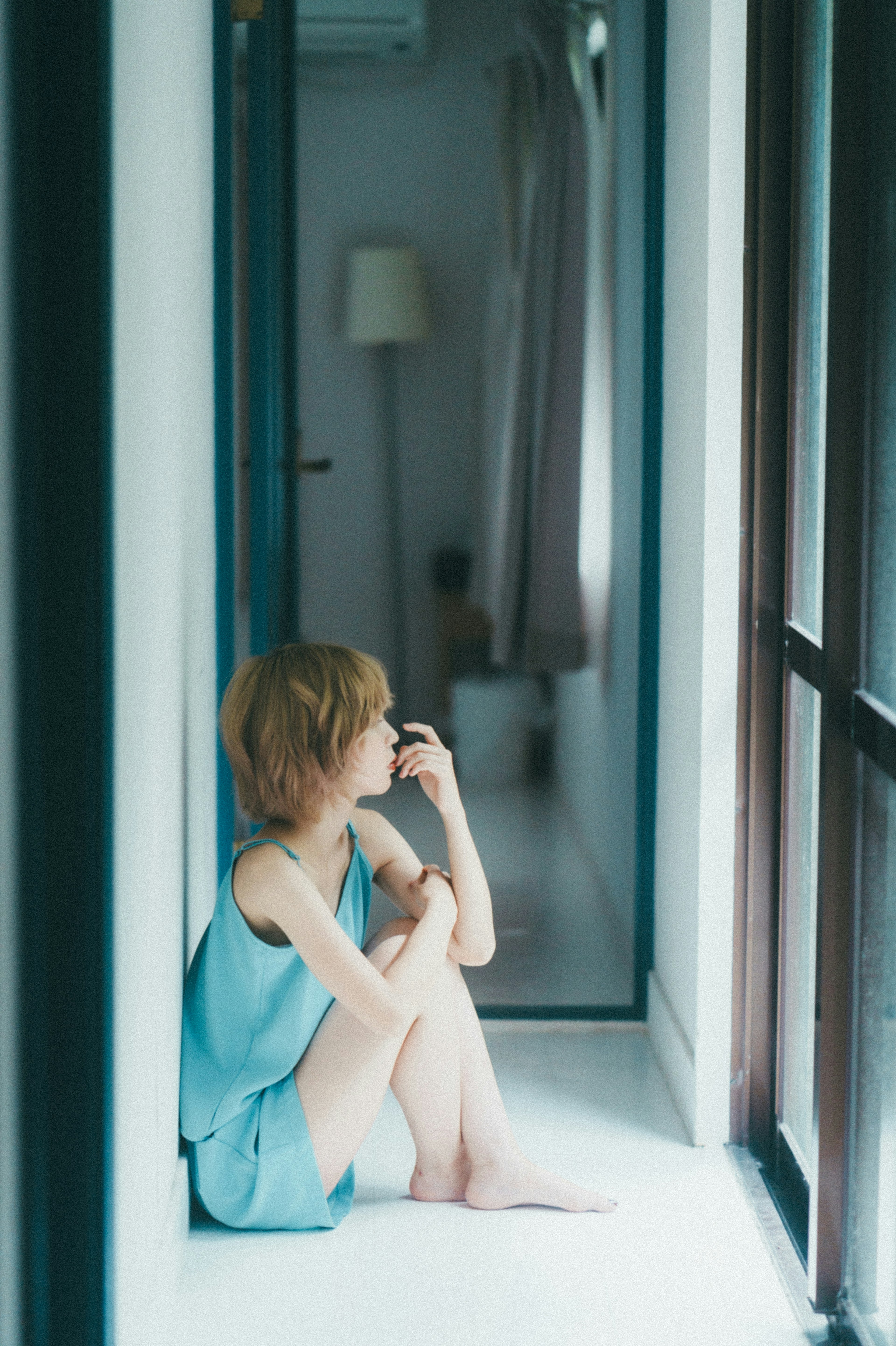 A woman in a blue outfit sitting in a hallway