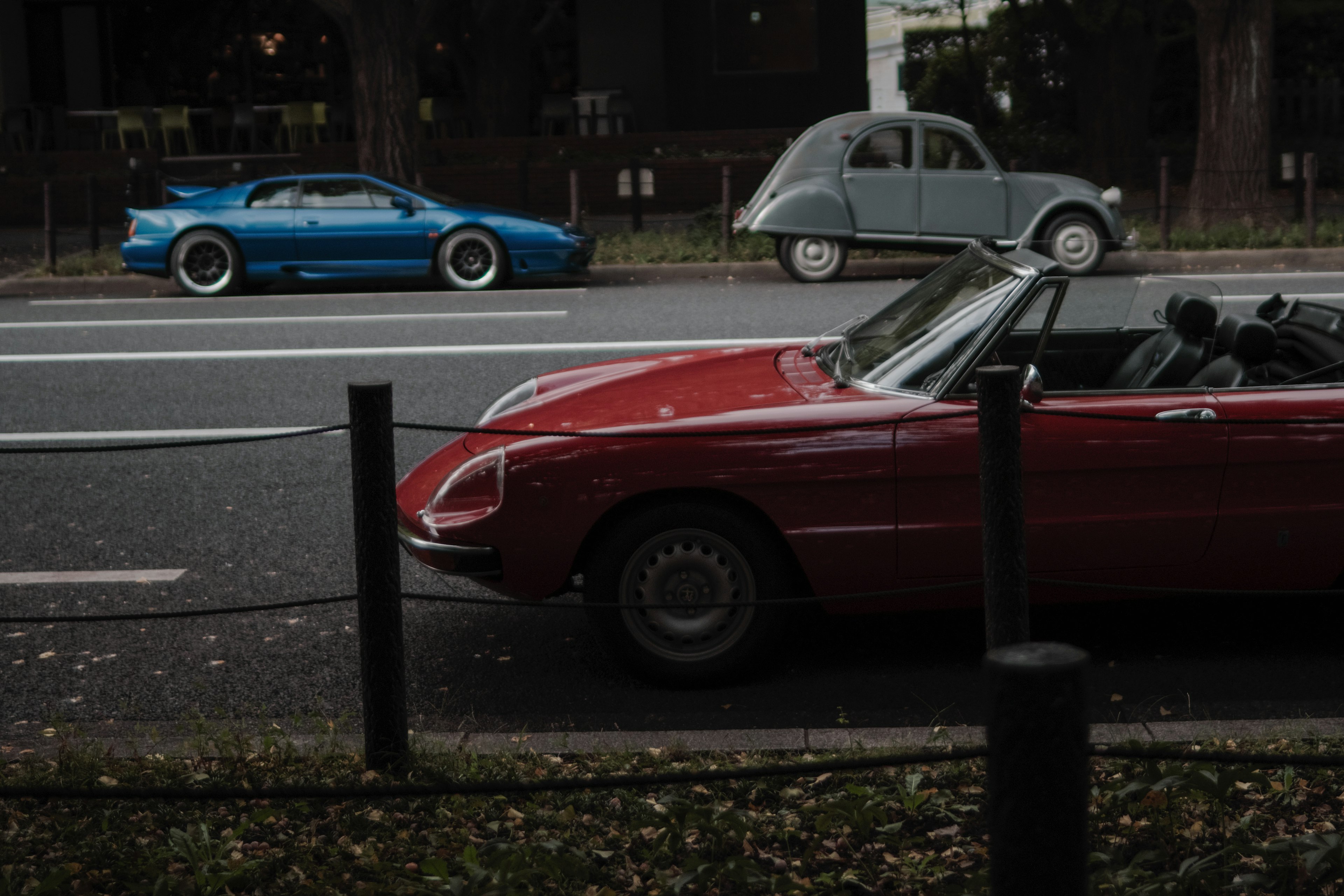 赤いスポーツカーと青いスーパーカーが並ぶ街の風景