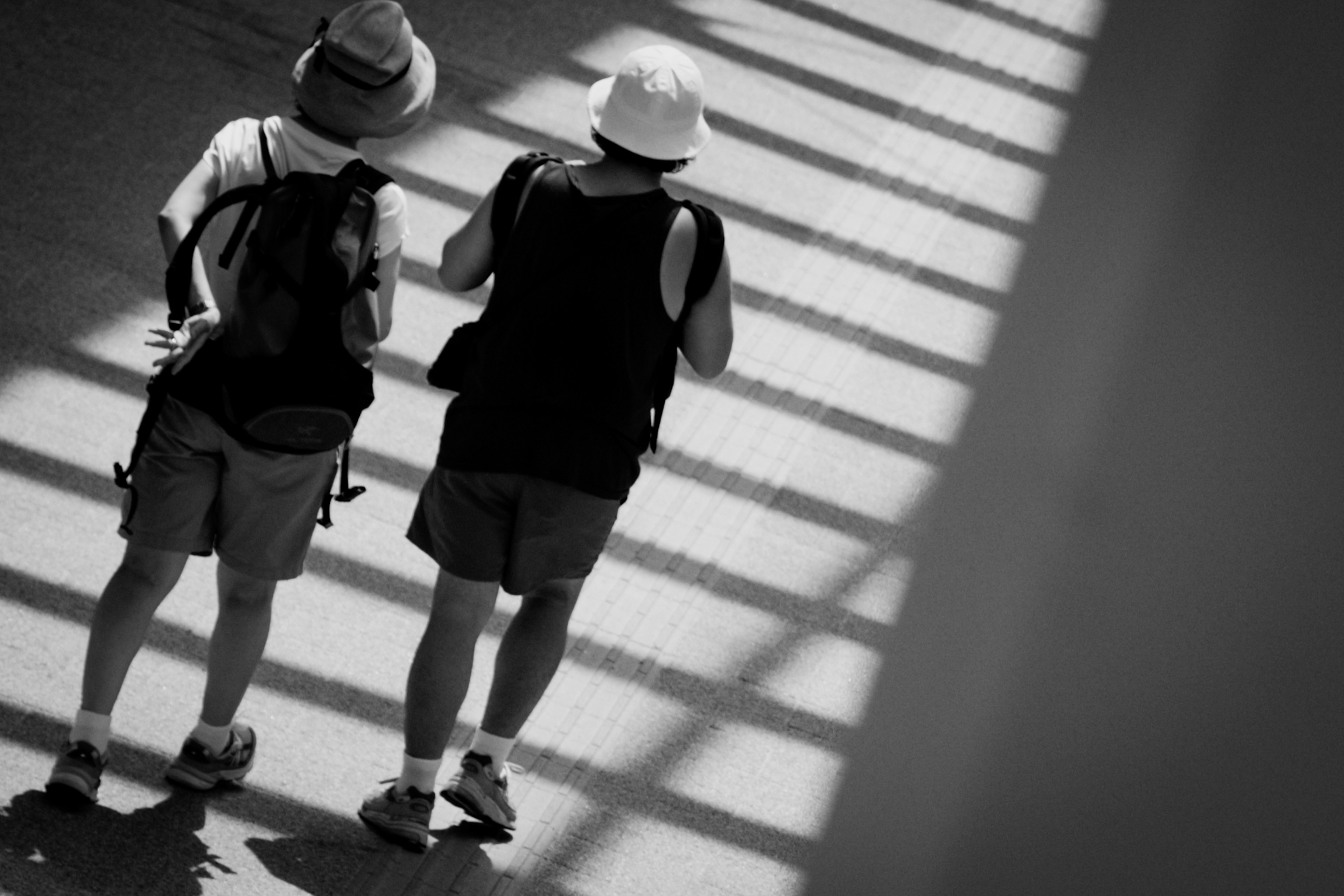 Dos turistas con sombreros caminando en la sombra en una foto en blanco y negro