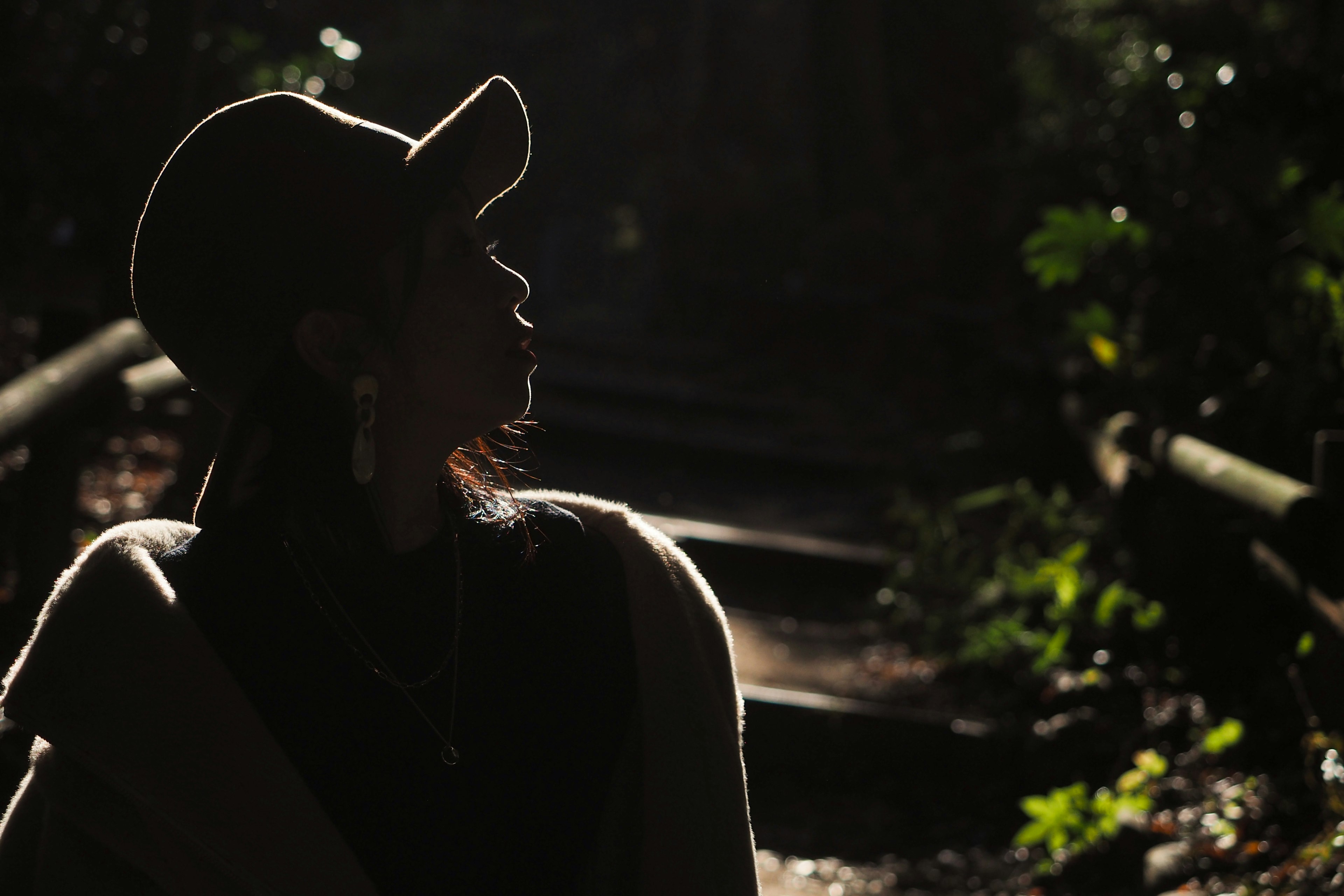 Silhouette d'une femme portant un chapeau regardant vers le haut dans un cadre naturel