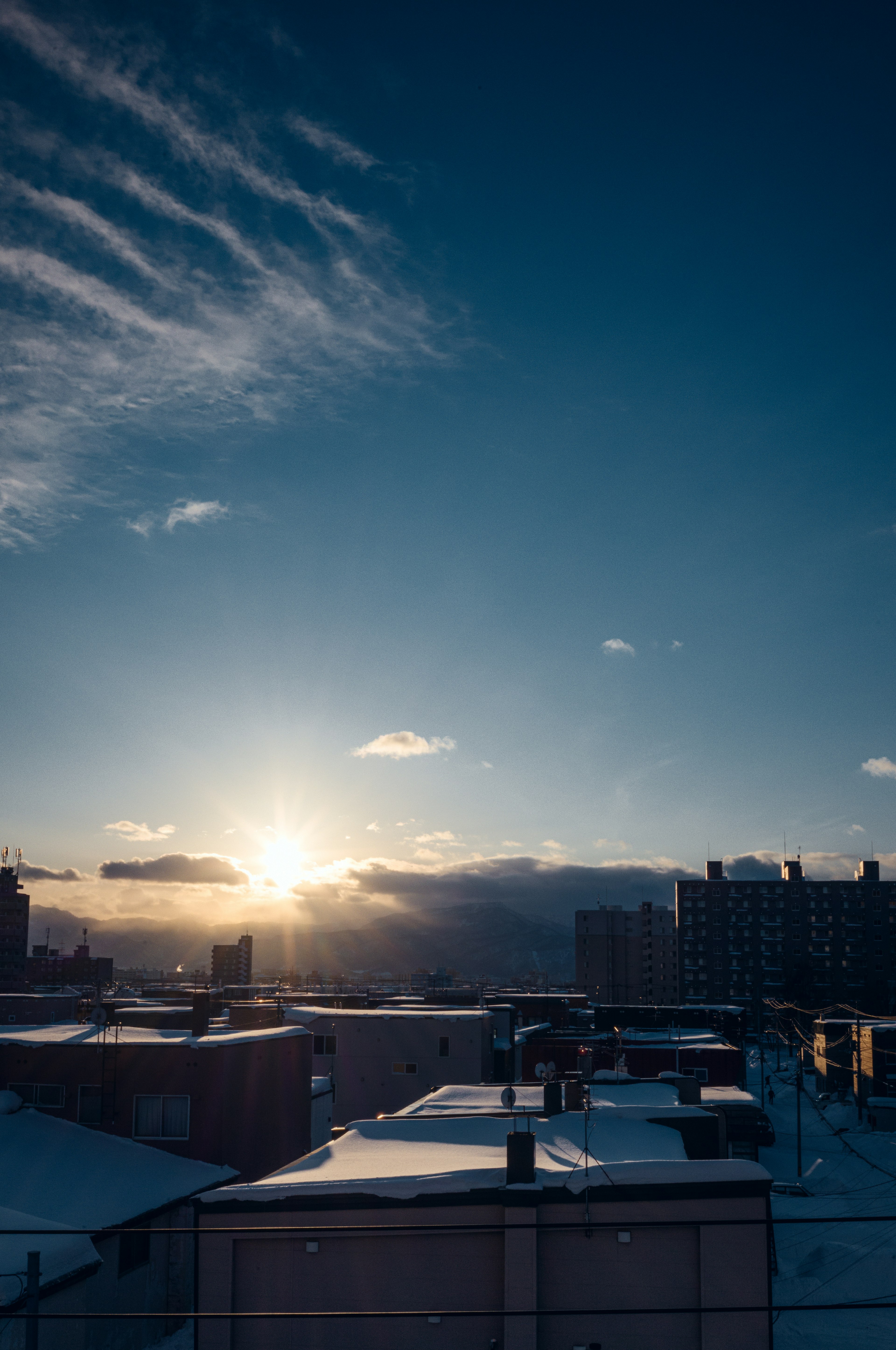 Amanecer sobre techos cubiertos de nieve bajo un cielo azul