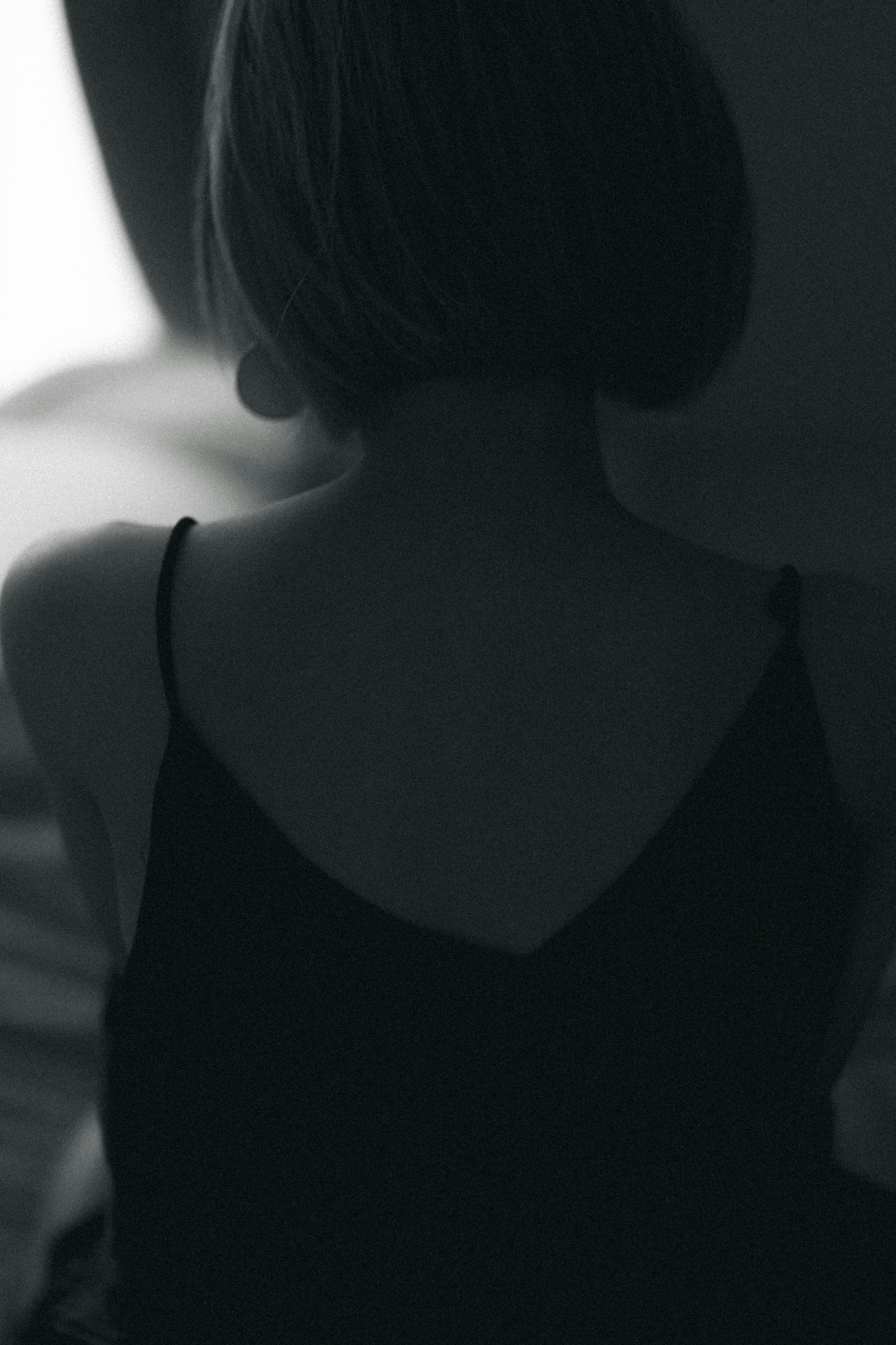 Monochrome image of a woman's back featuring a short hairstyle and a slip dress