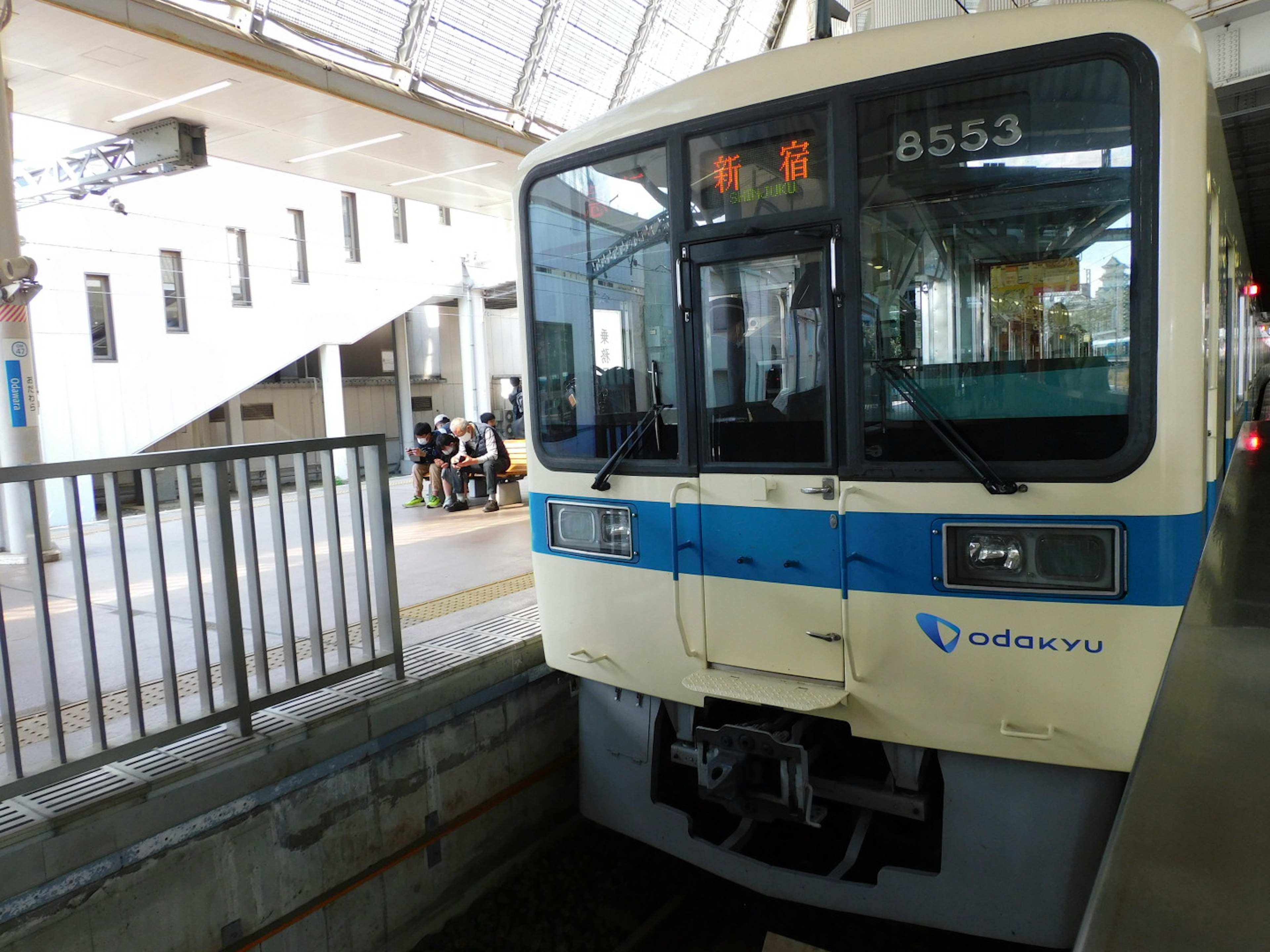 駅に停車中の青いラインのある白い電車