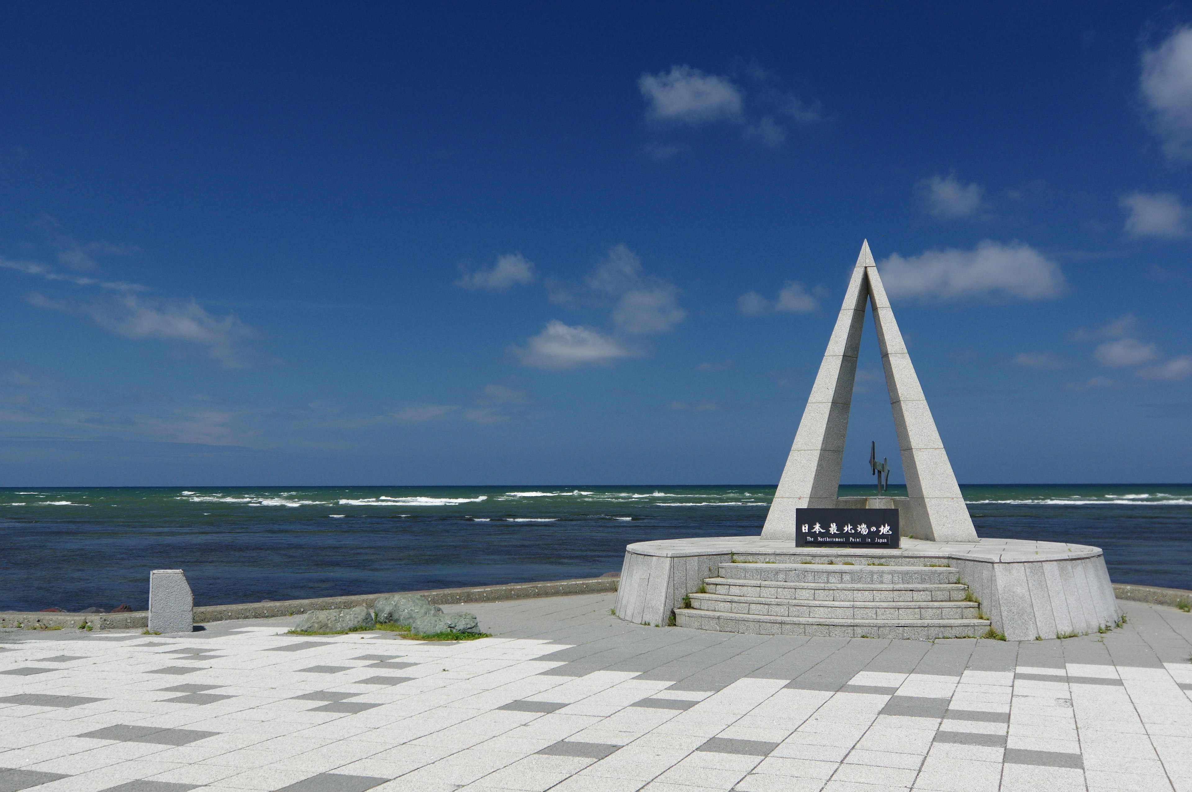 Triangular monument near the ocean under a clear blue sky