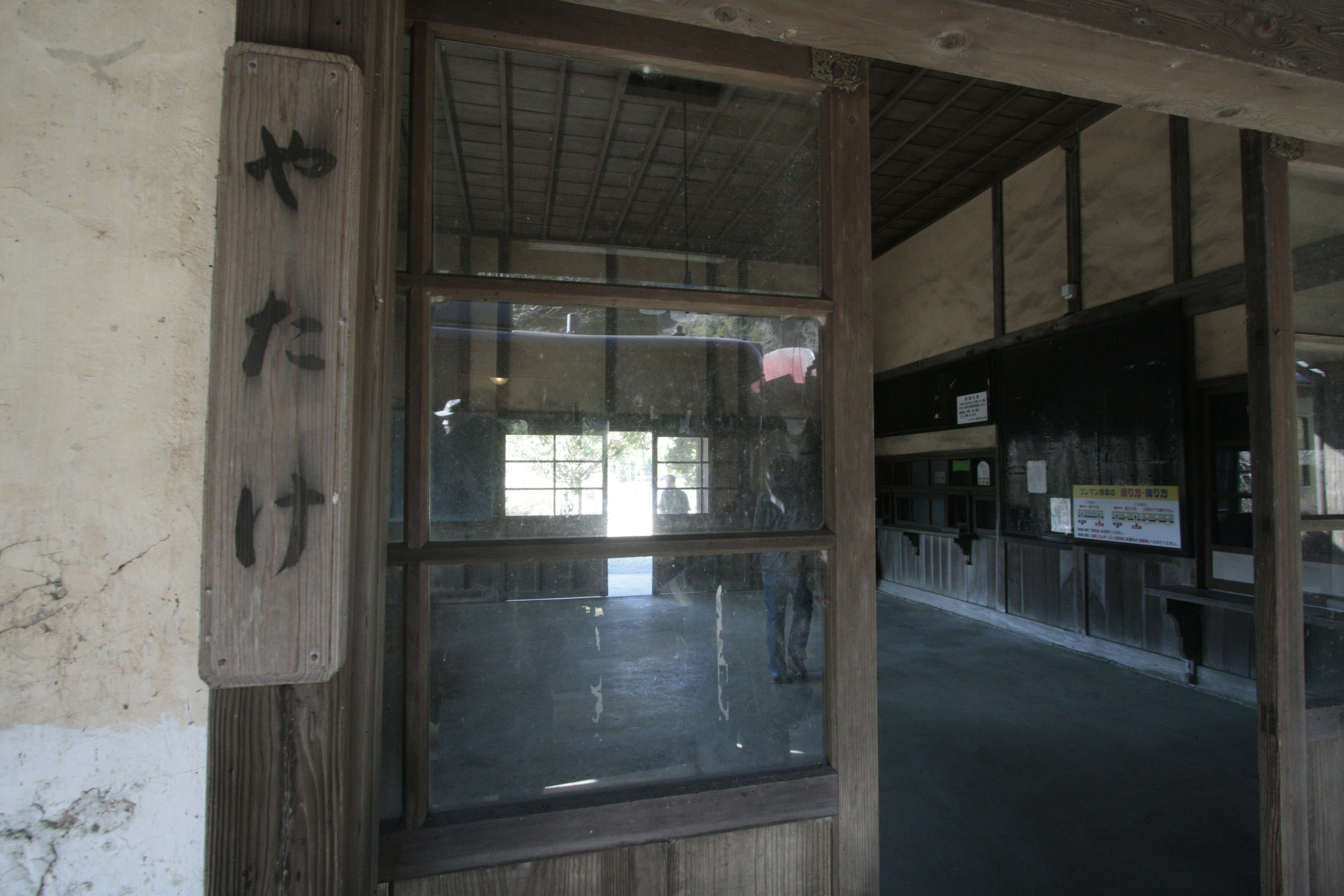 Entrée d'un ancien bâtiment en bois avec une porte en verre et un panneau indiquant yakake