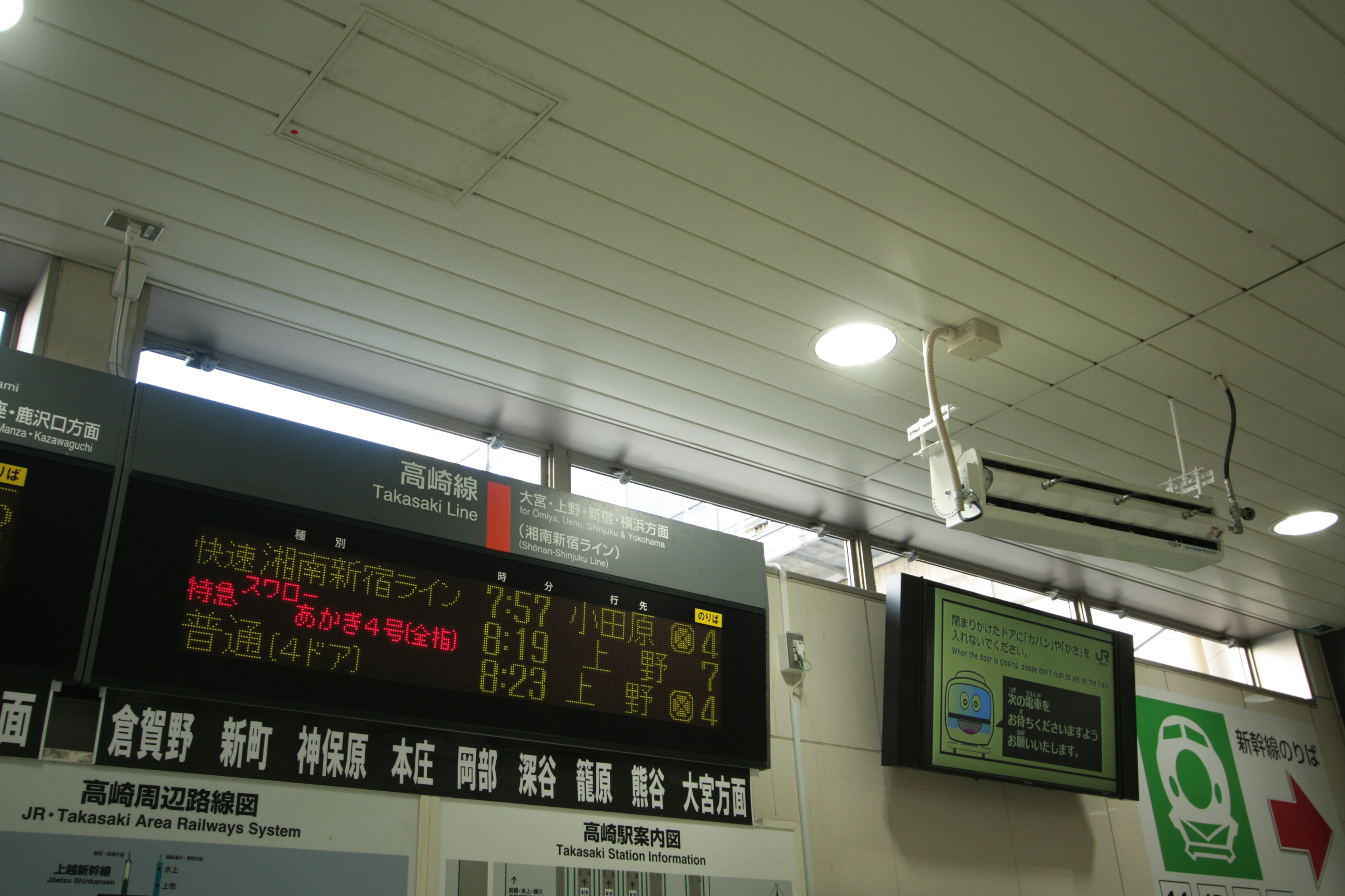 Vue intérieure d'une gare montrant des panneaux d'affichage et des unités de climatisation