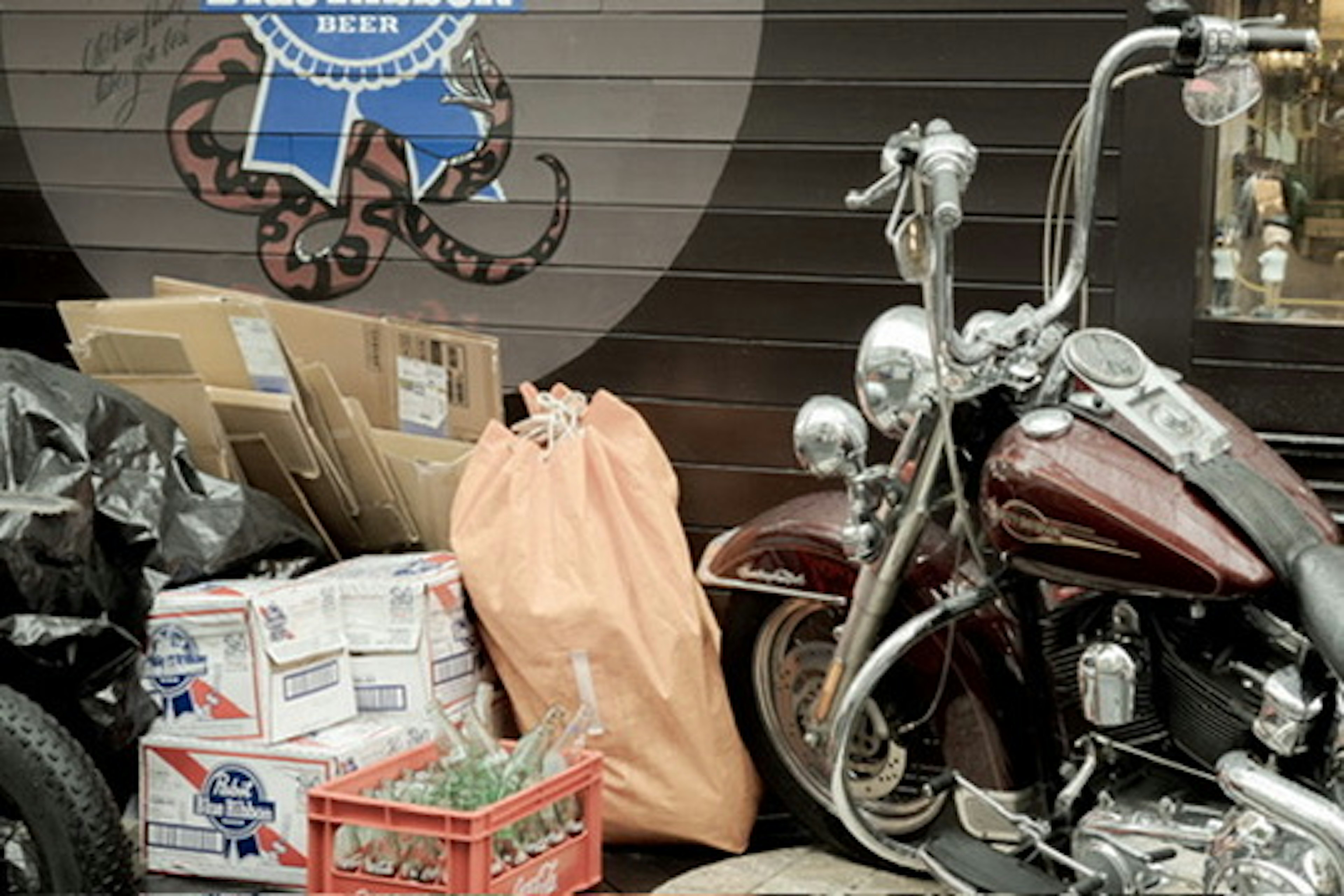 A vintage motorcycle beside an orange bag and boxes in an urban setting