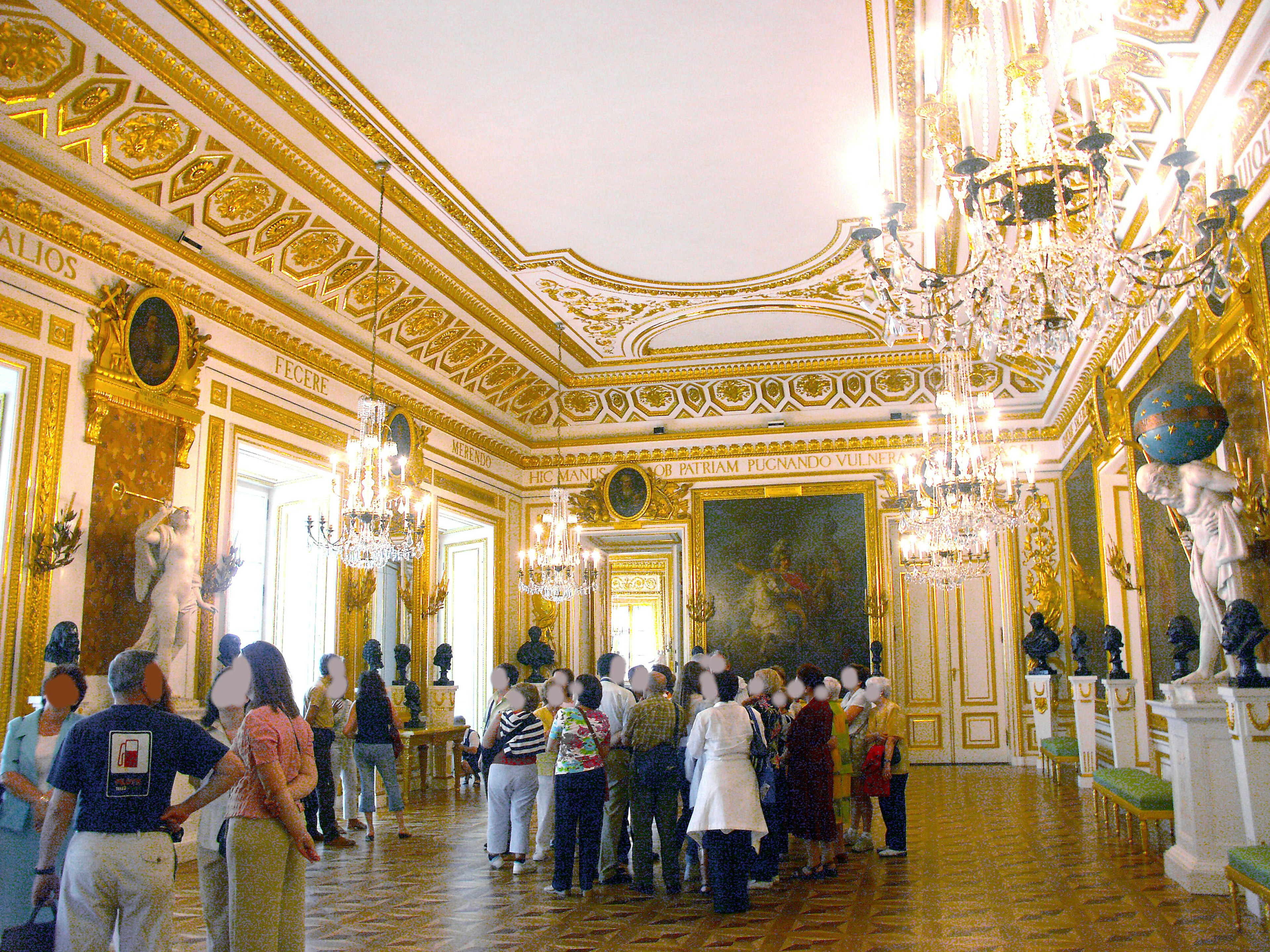 Crowd of tourists in an ornate room with chandeliers and artwork