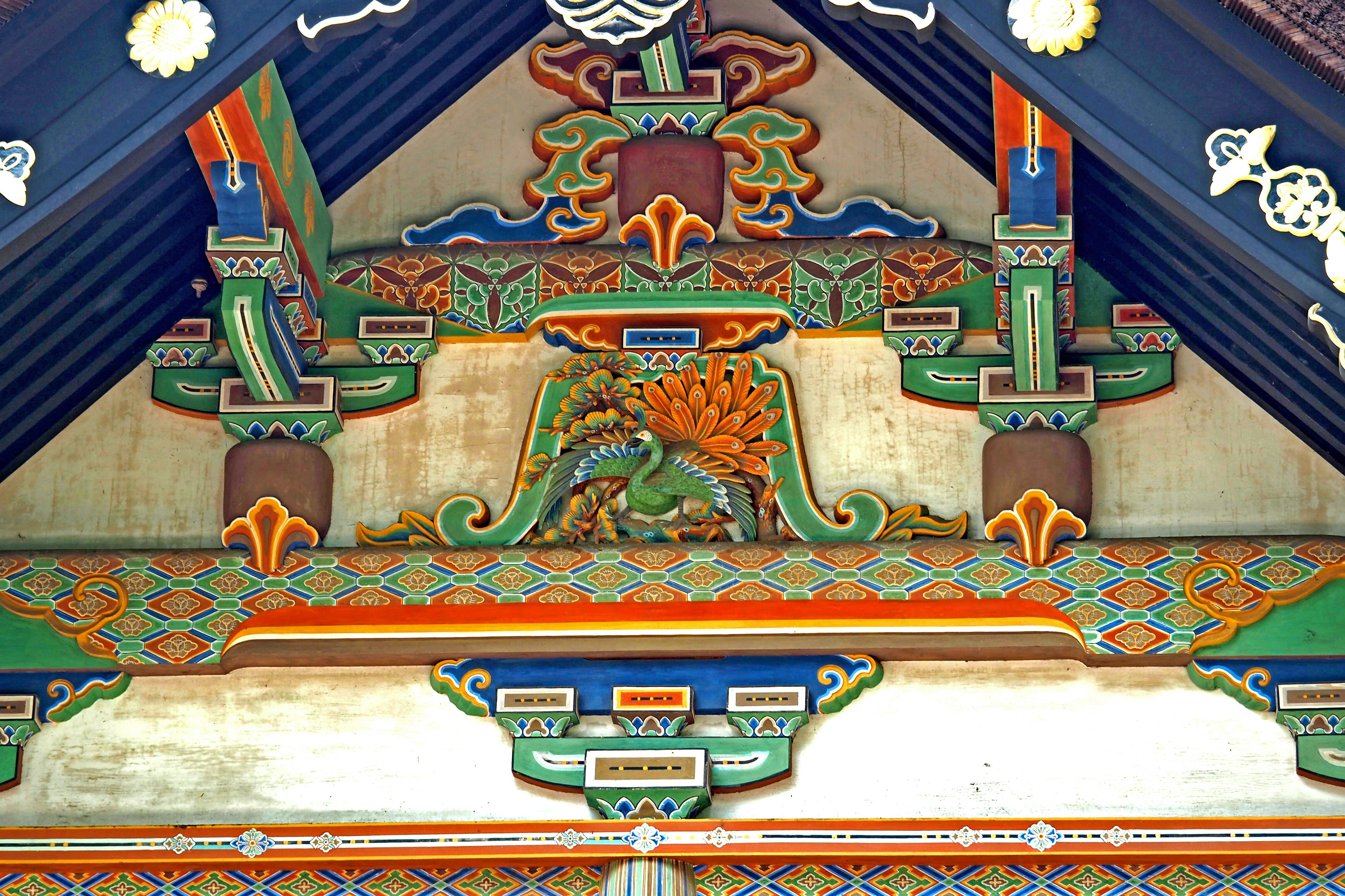 Colorful decorative elements on a traditional building roof featuring a beautiful bird sculpture in the center