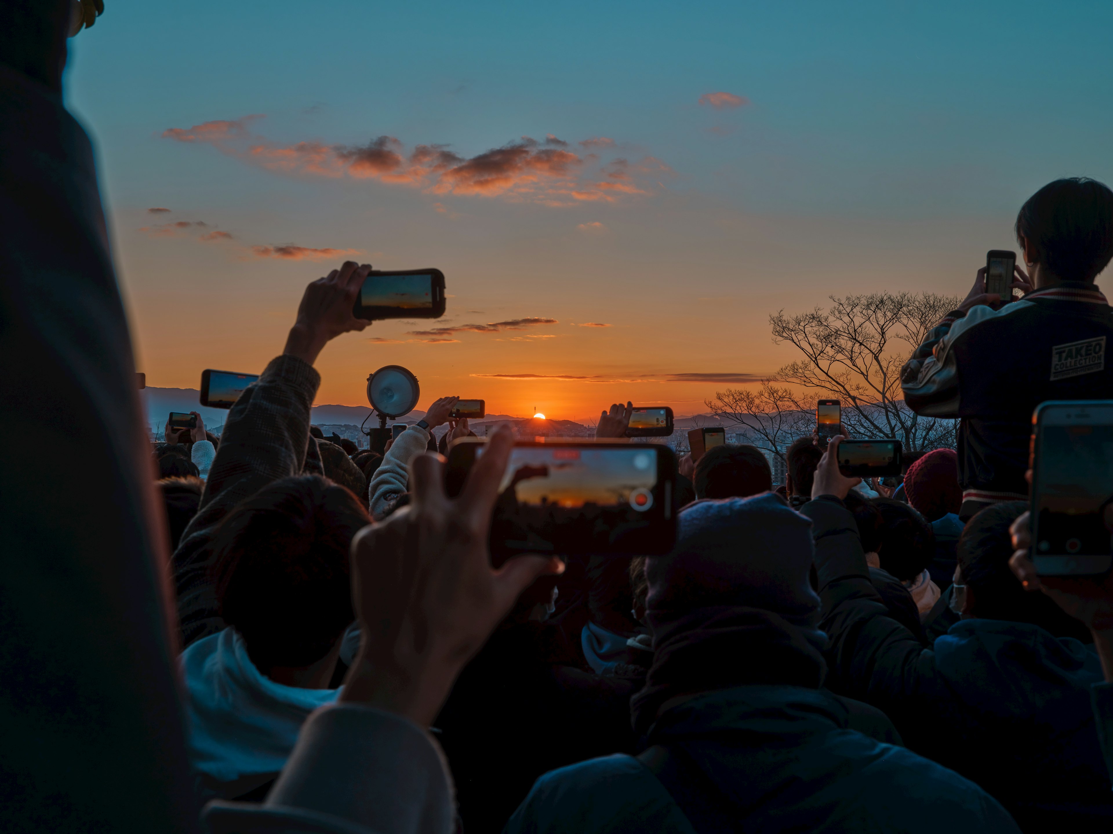 夕日を撮影する人々の群れとスマートフォン