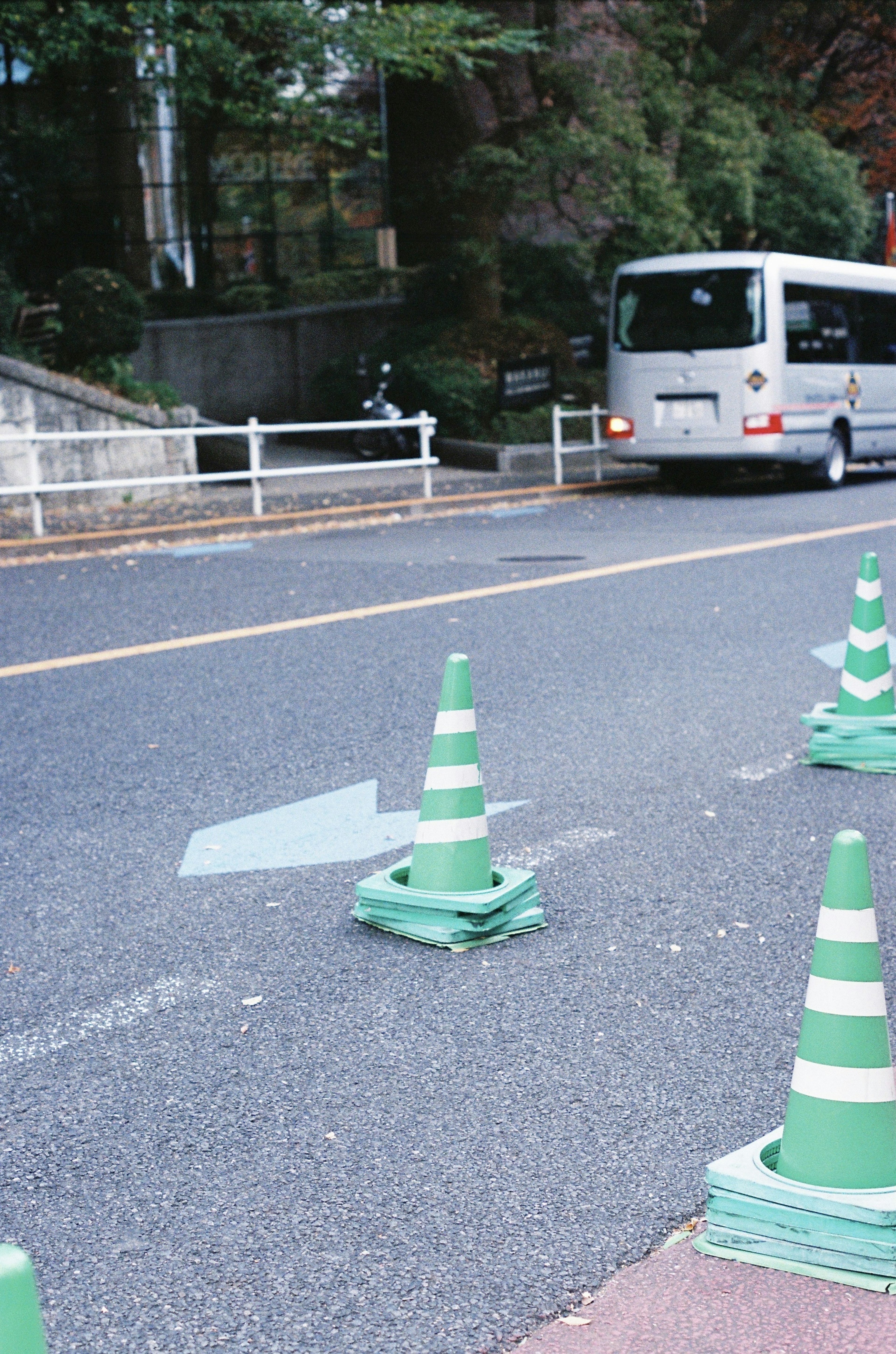 Pemandangan jalan dengan kerucut lalu lintas hijau dan bus yang lewat