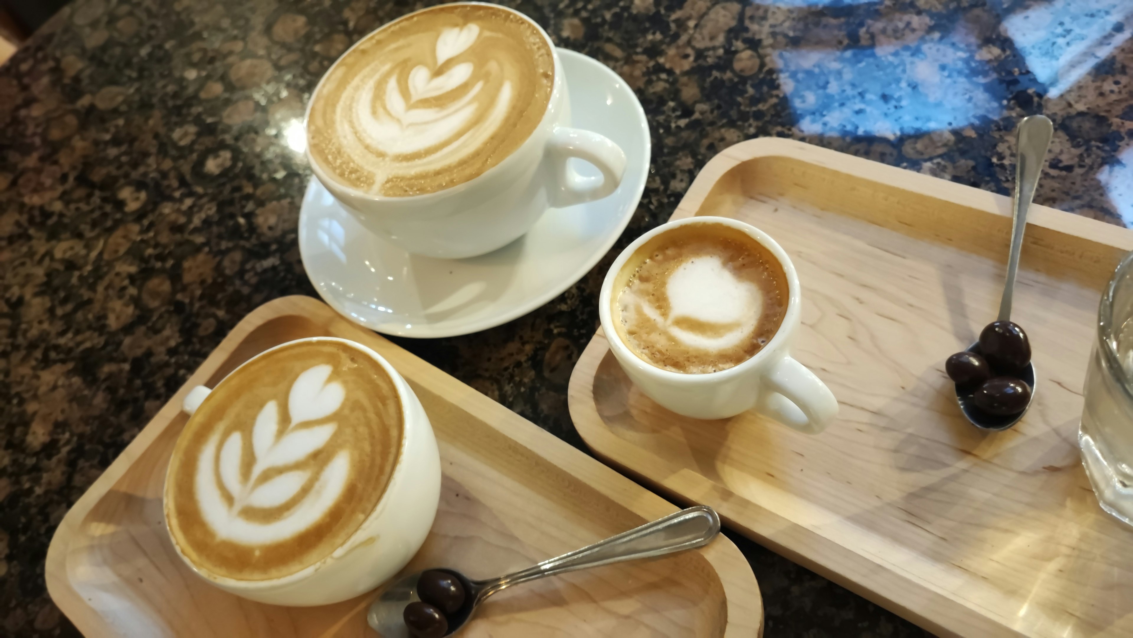 Tres tazas de café con arte latte en una bandeja de madera