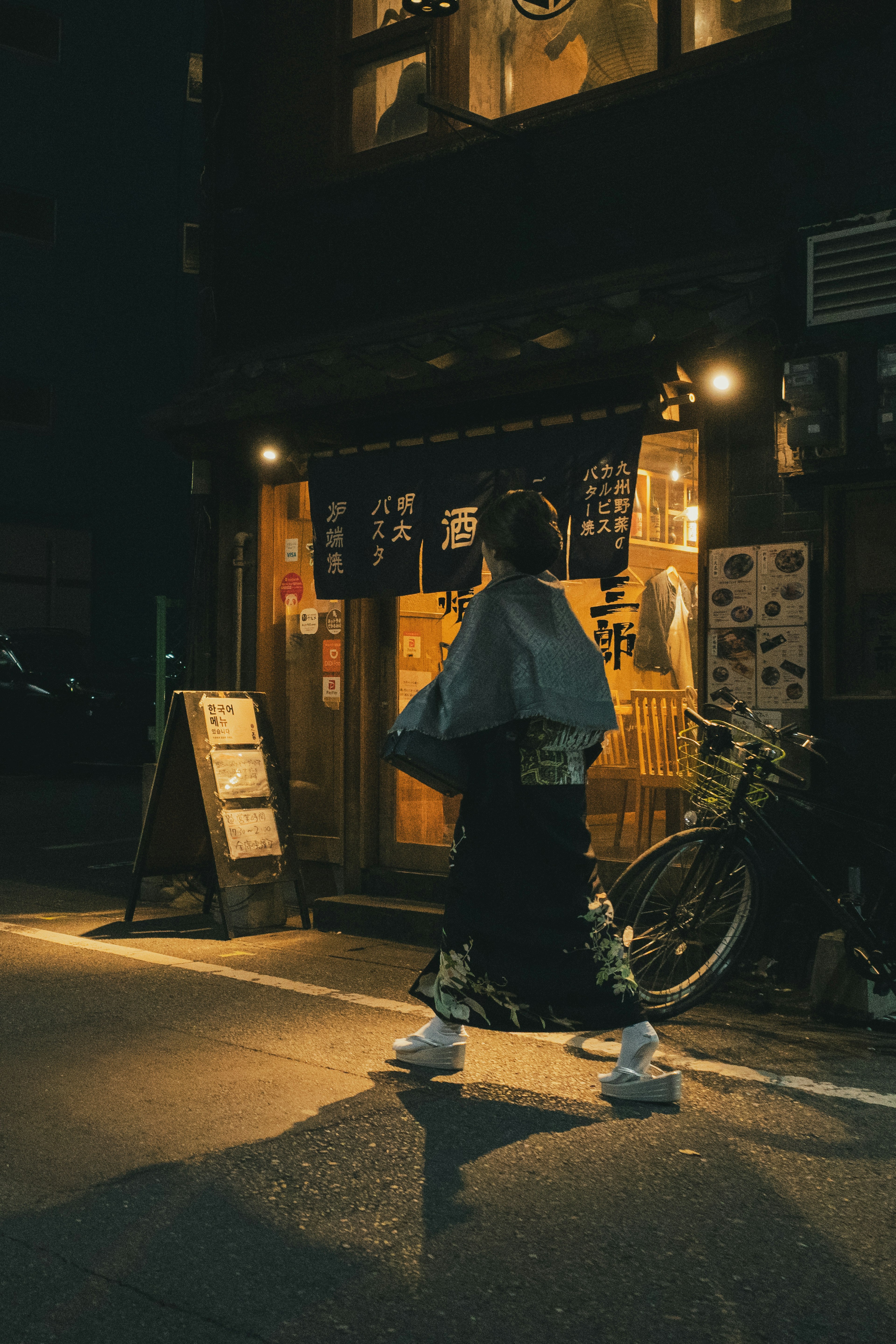 夜の街を歩く着物姿の女性と和風の店舗