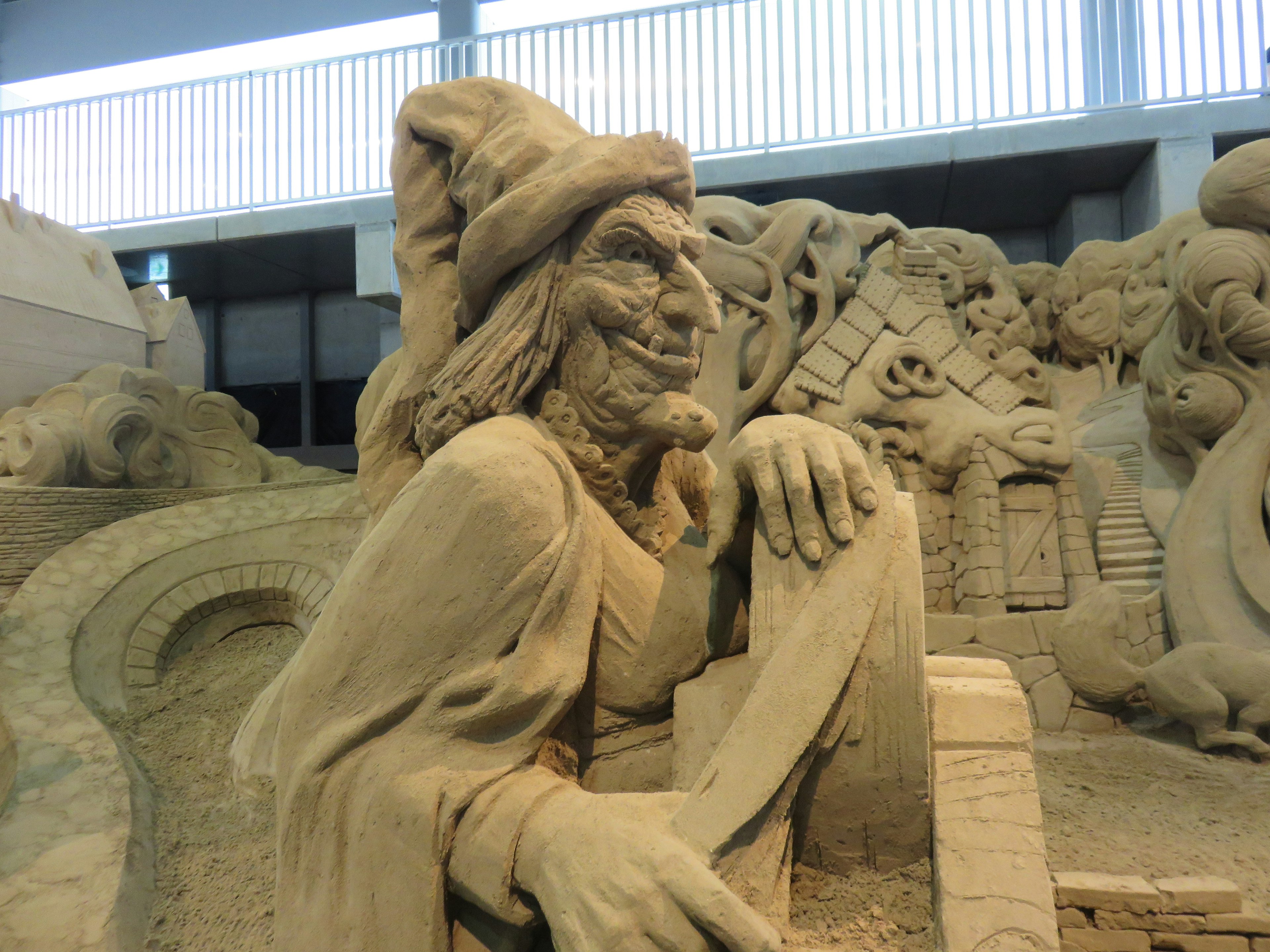 Sculpture de sable détaillée d'un sorcier portant un chapeau avec des motifs complexes en arrière-plan