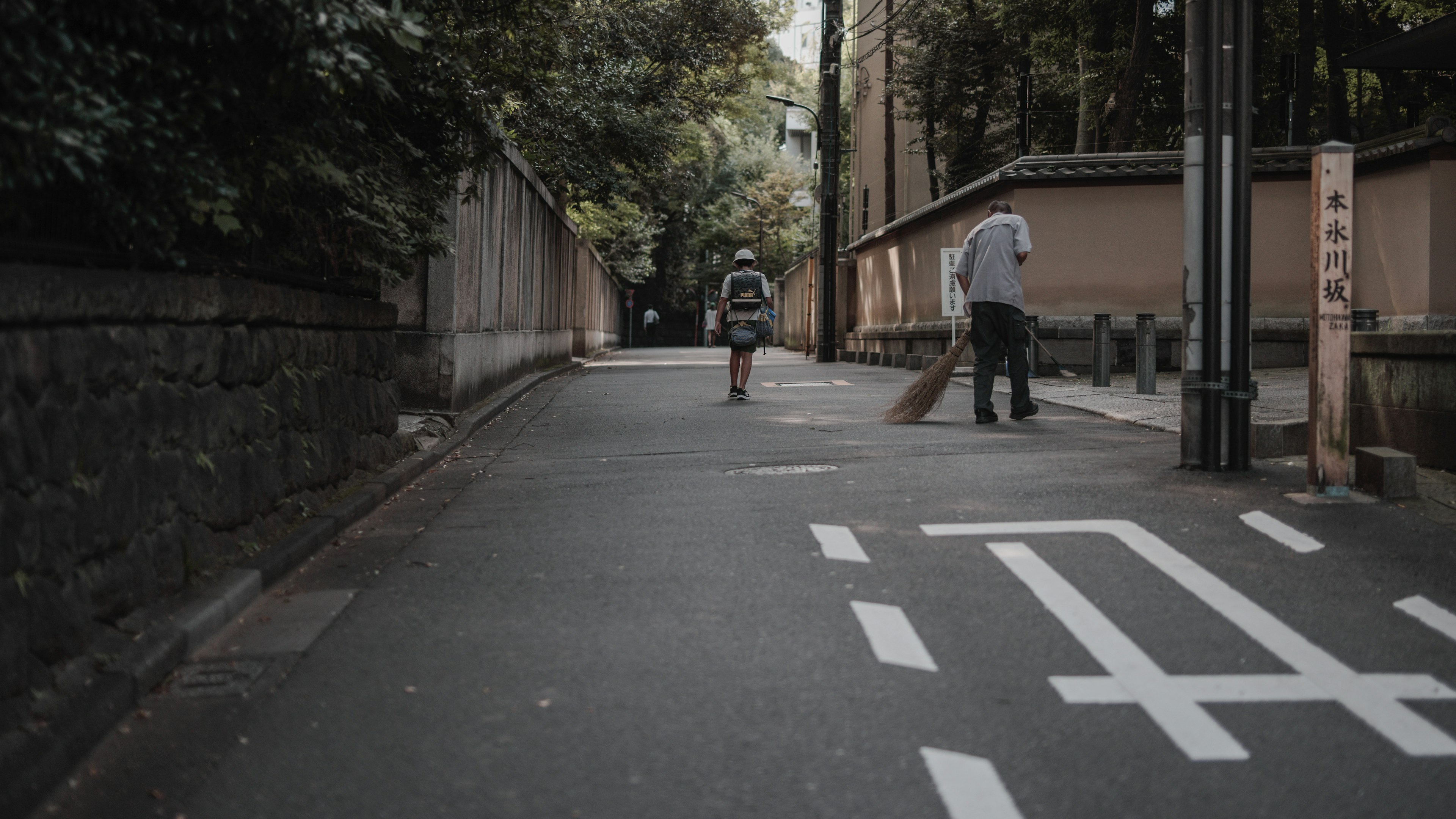 Escena de una calle tranquila con una persona caminando y otra en bicicleta