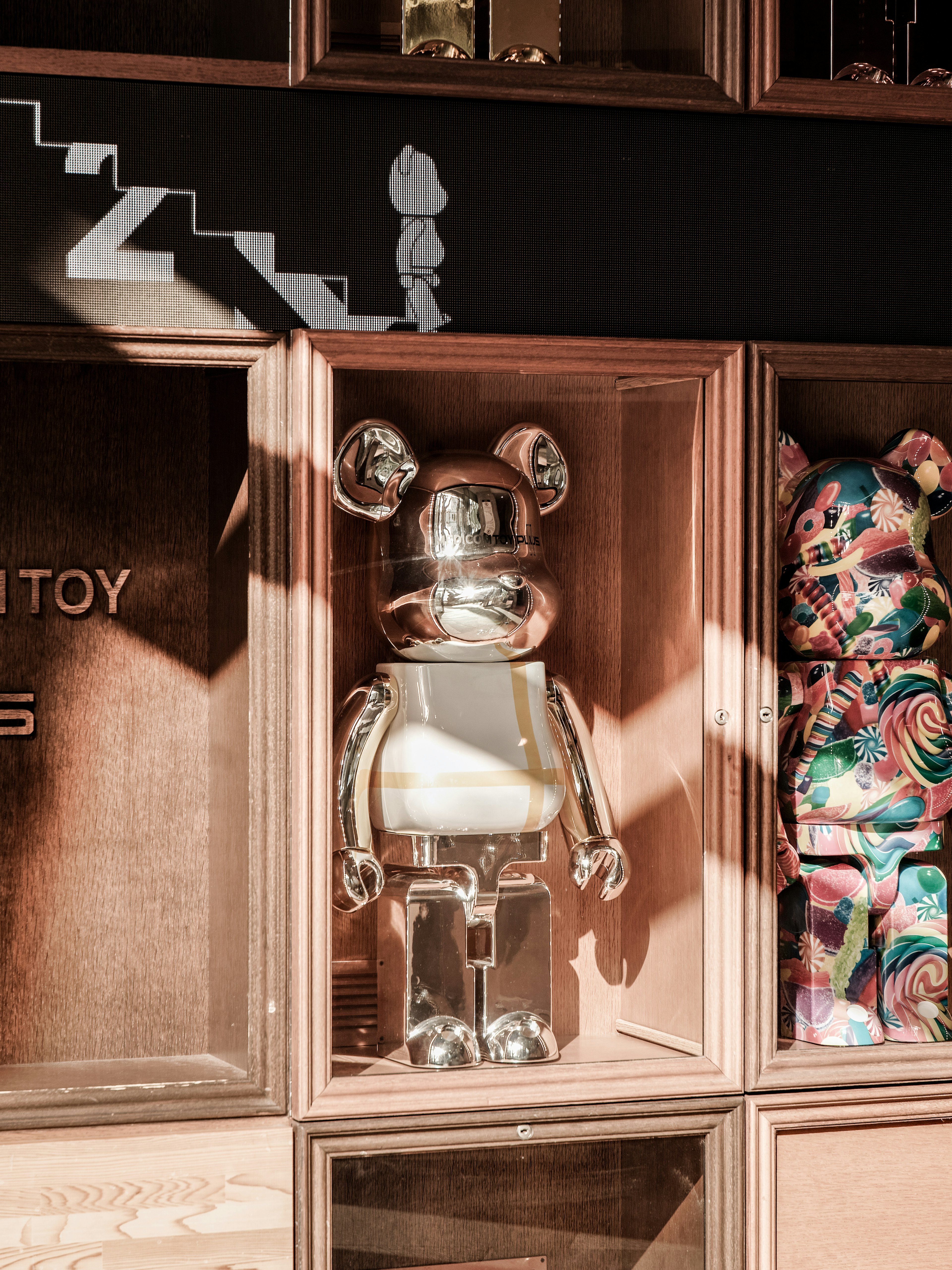 Figurines Bearbrick argentées et colorées exposées dans une vitrine