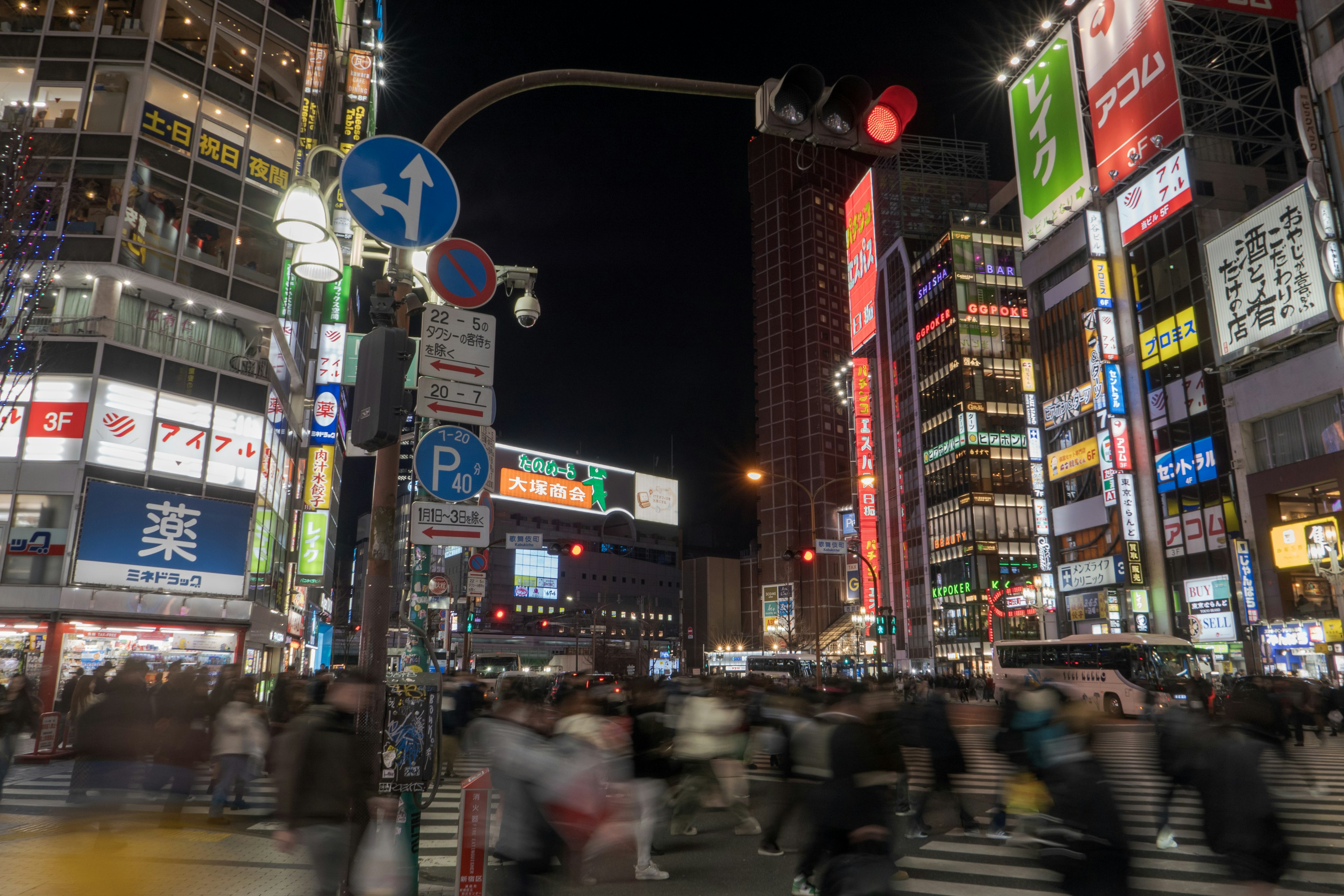 Busy street at night with people crossing and bright neon signs