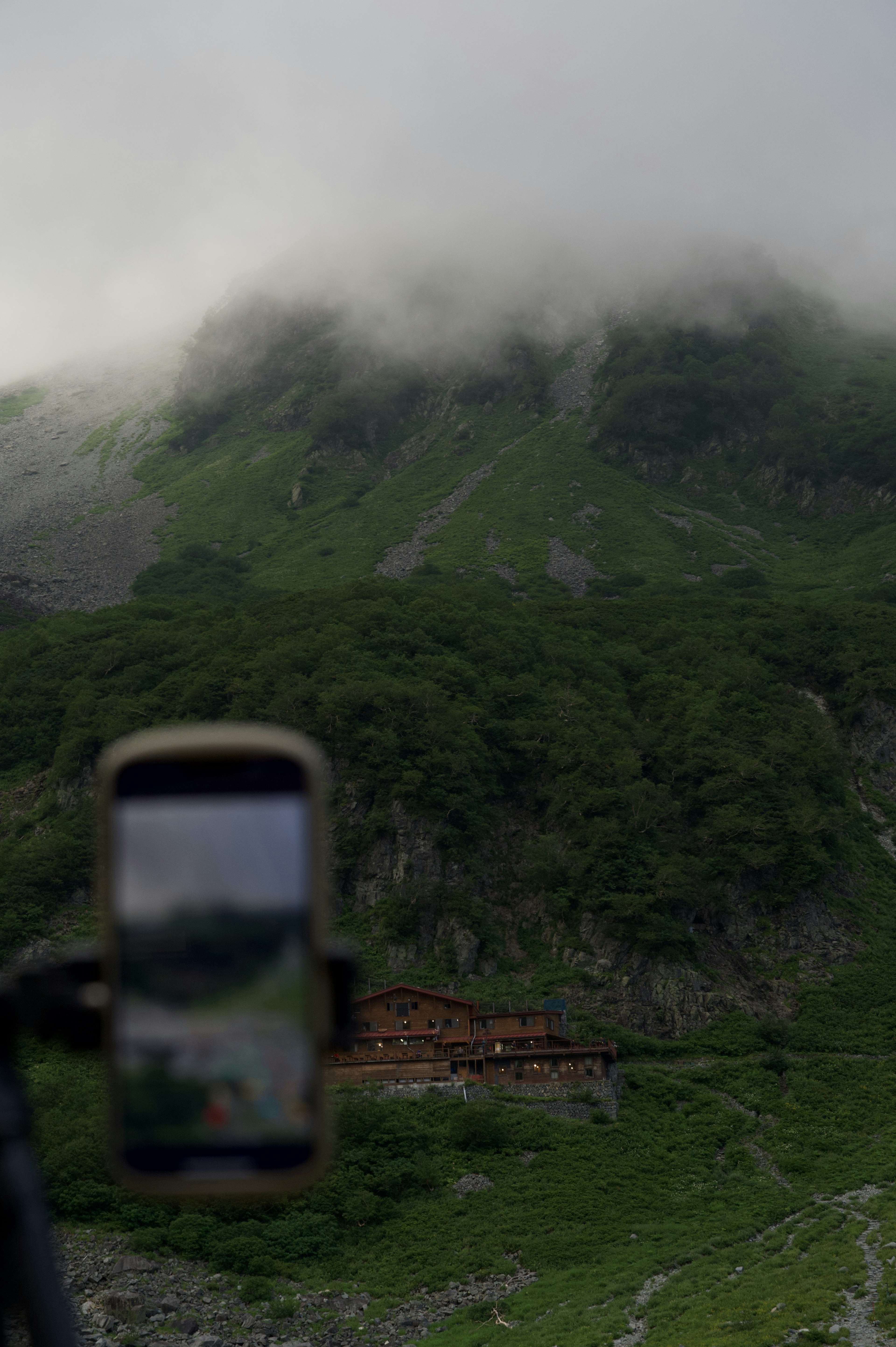 霧に覆われた山と緑の風景とスマートフォンの画像