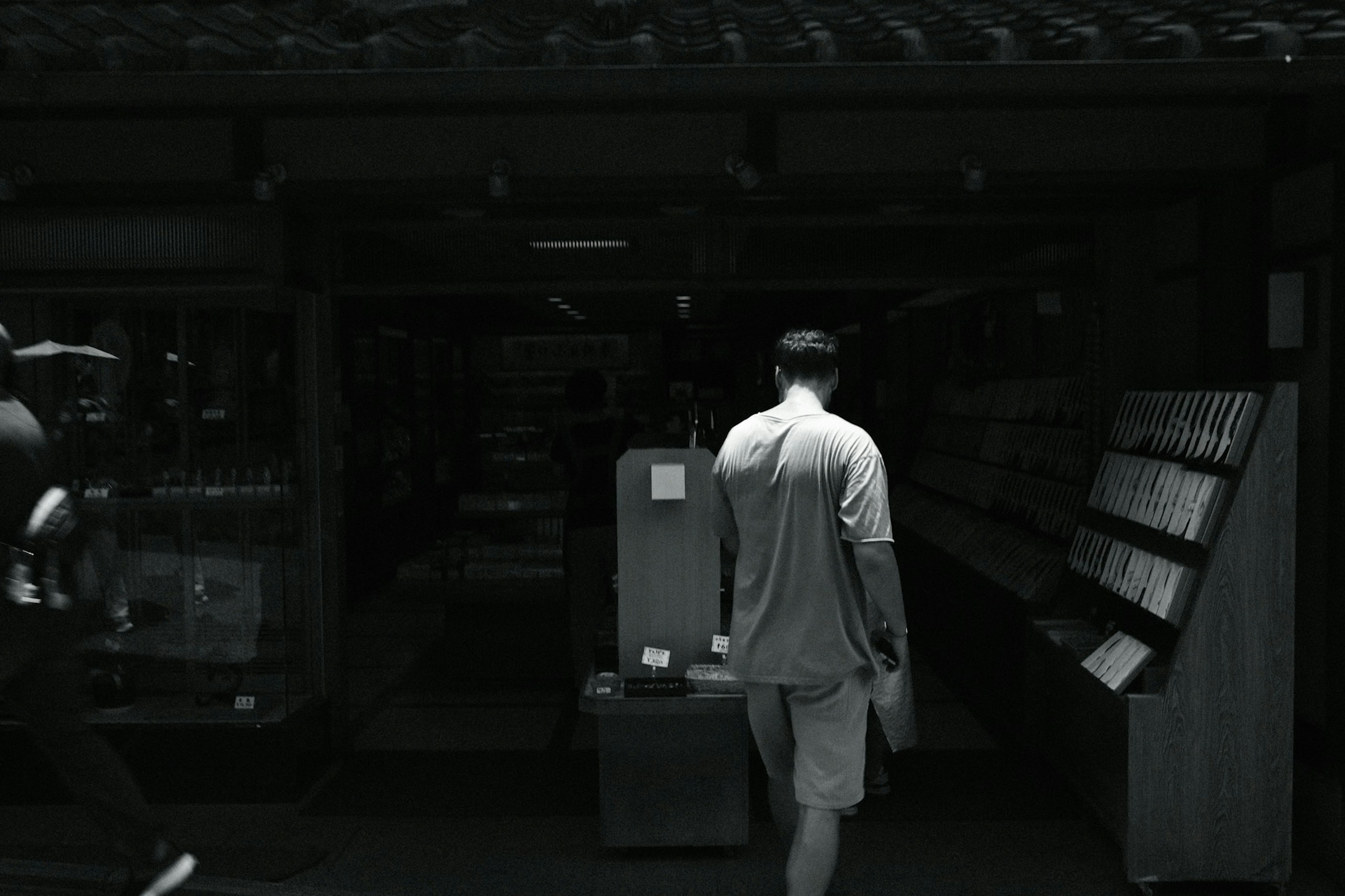 A person walking towards the entrance of a shop in a monochrome image