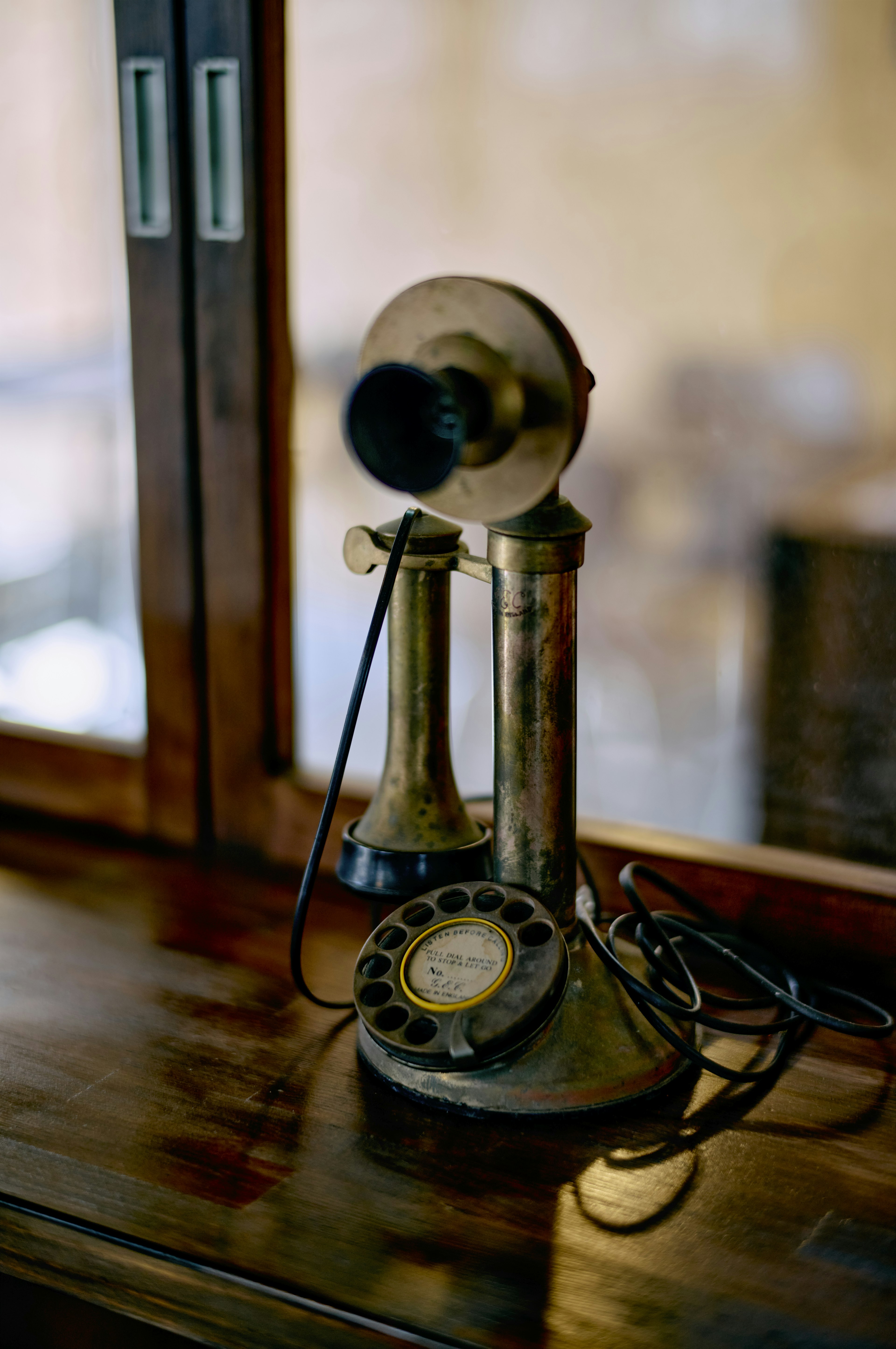 An antique telephone placed by a window