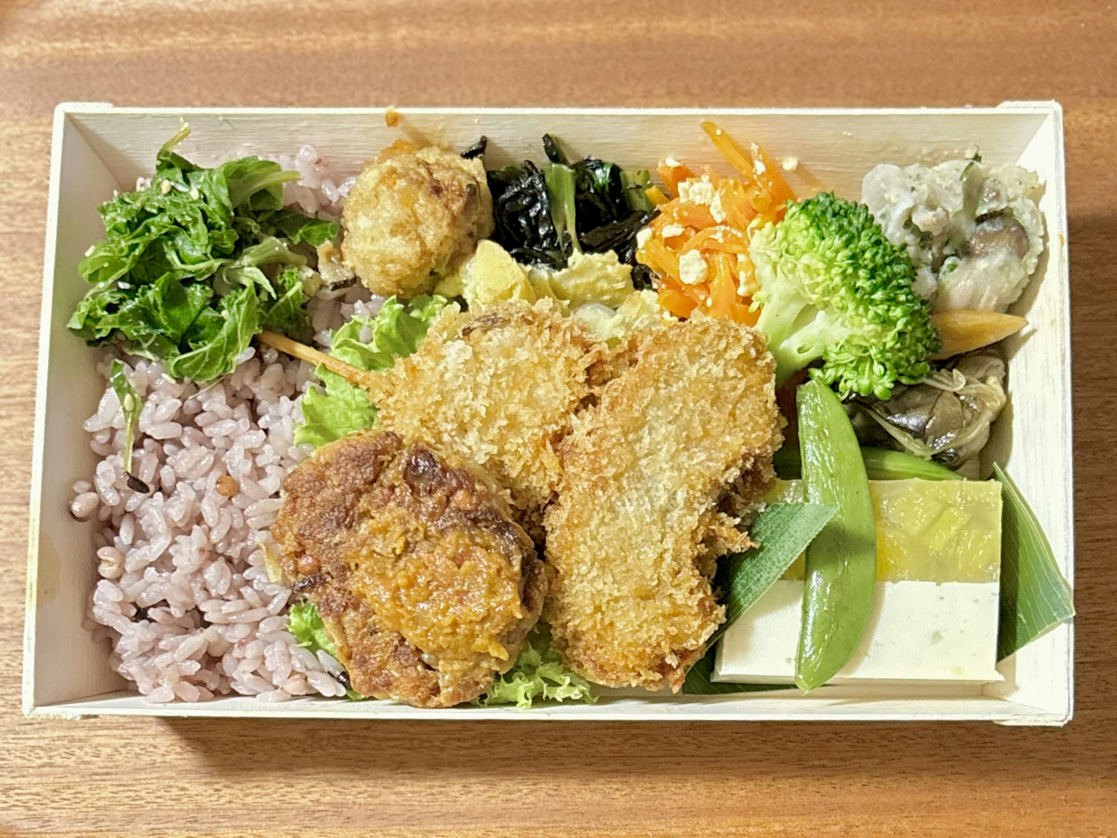 Caja bento japonesa colorida con alimentos fritos verduras y arroz integral