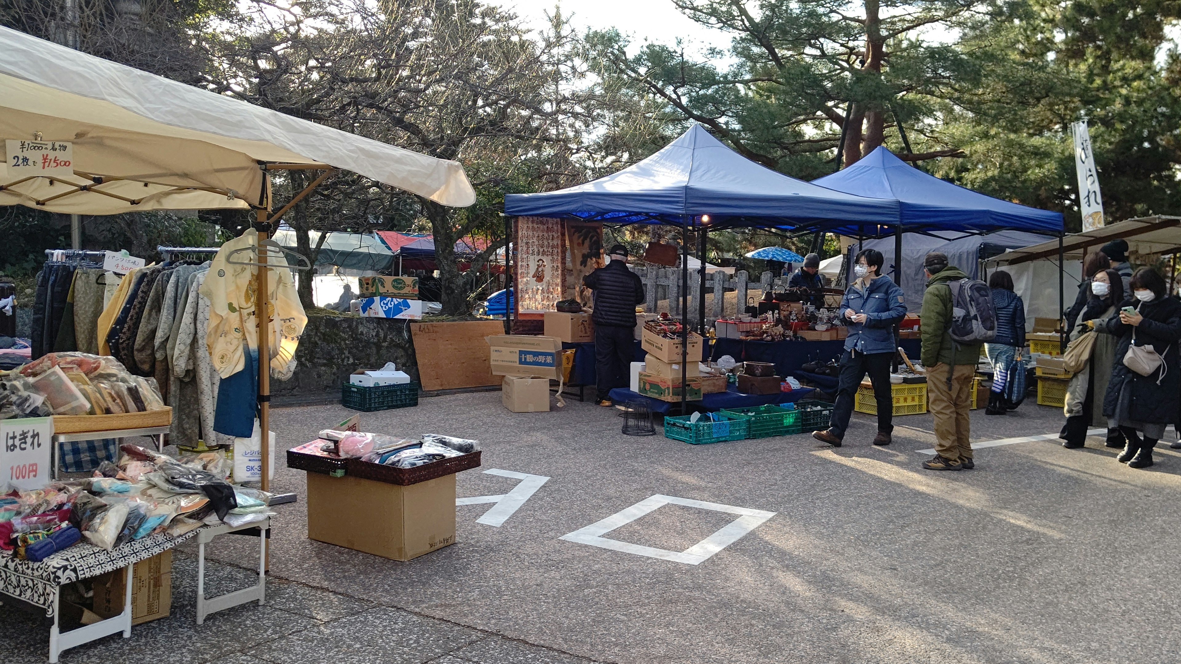 Scena di un mercato delle pulci con bancarelle e persone che fanno acquisti