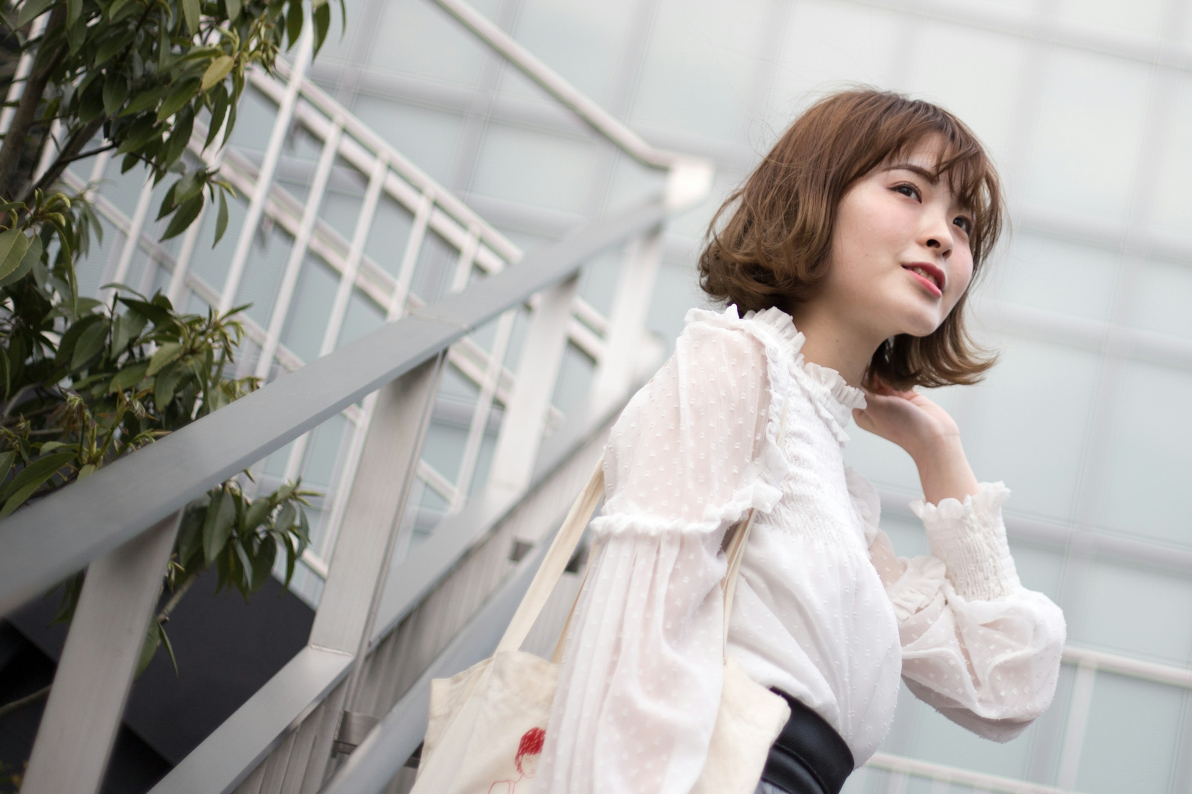 Side profile of a woman climbing stairs wearing a white blouse and black skirt