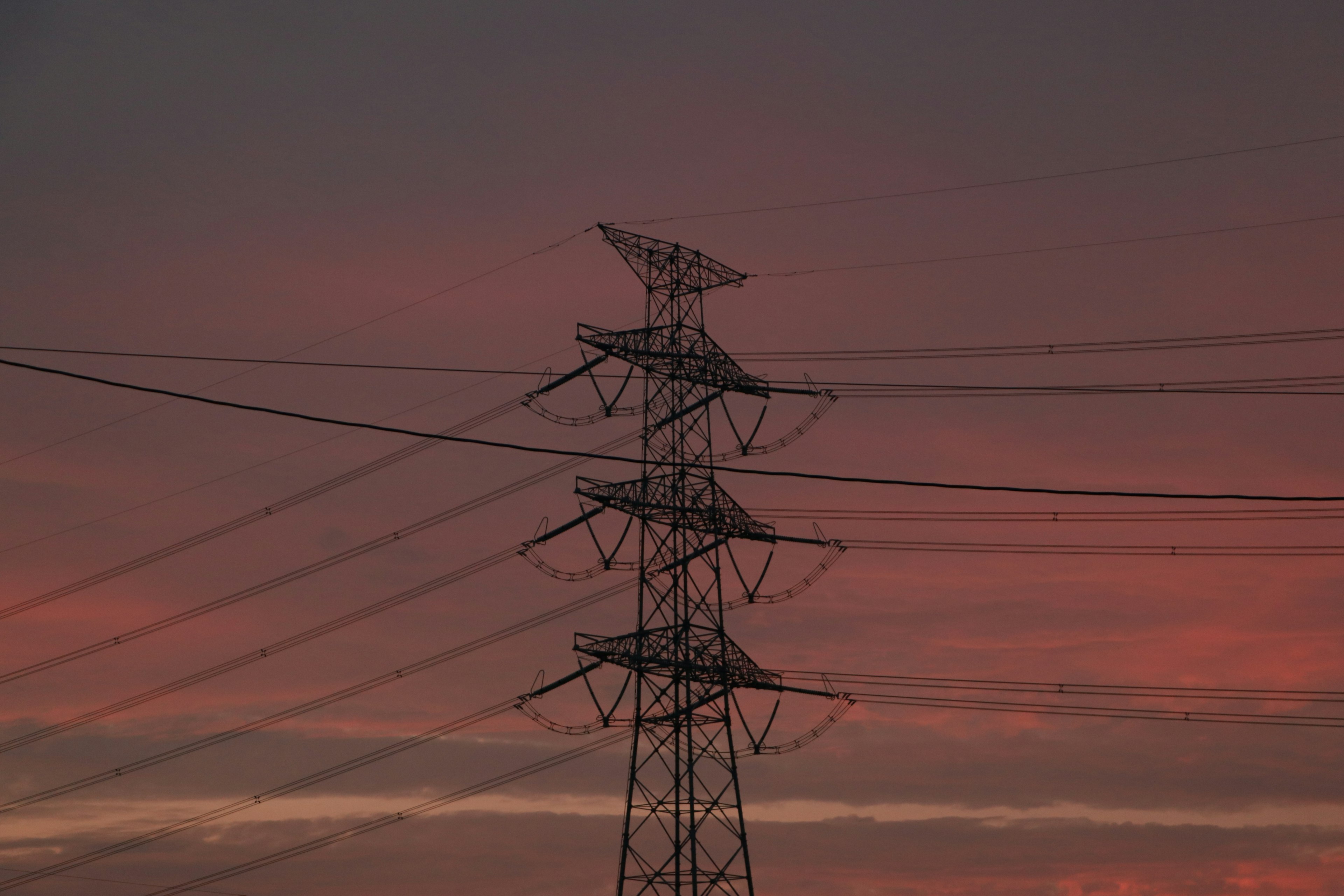 Silhouette of a power tower against a sunset sky