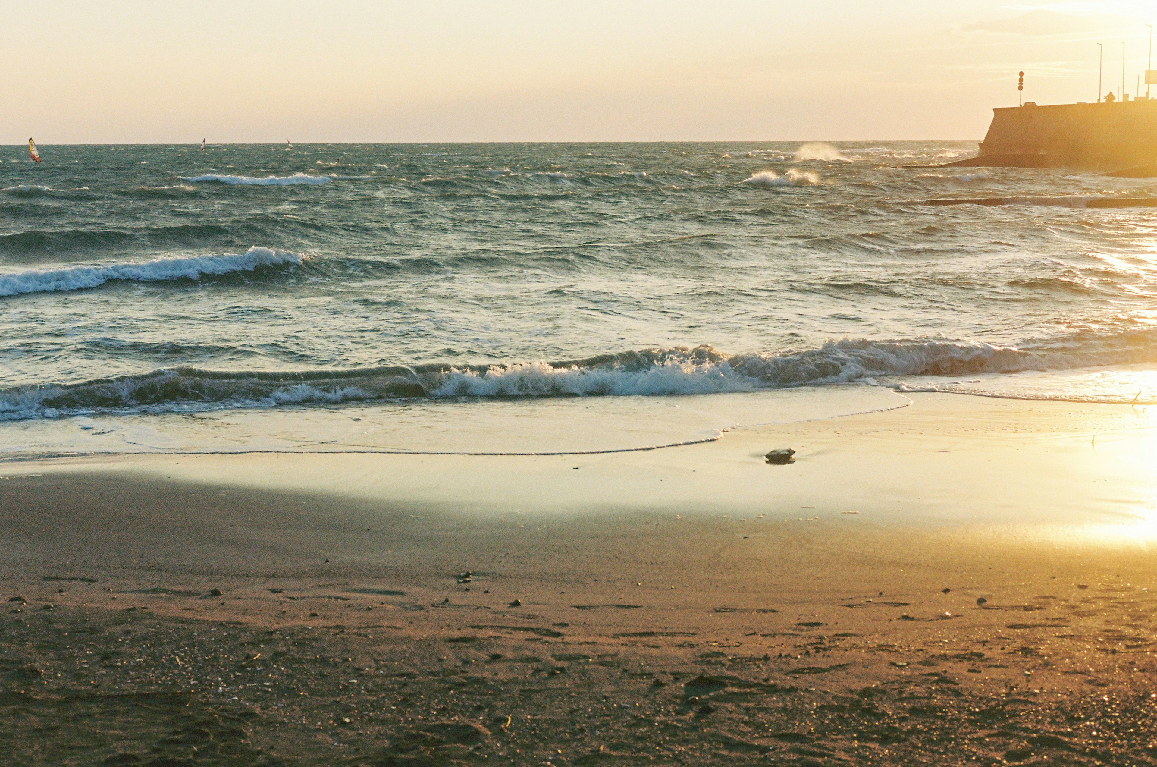 Strand bei Sonnenuntergang mit sanften Wellen und weichem Sand