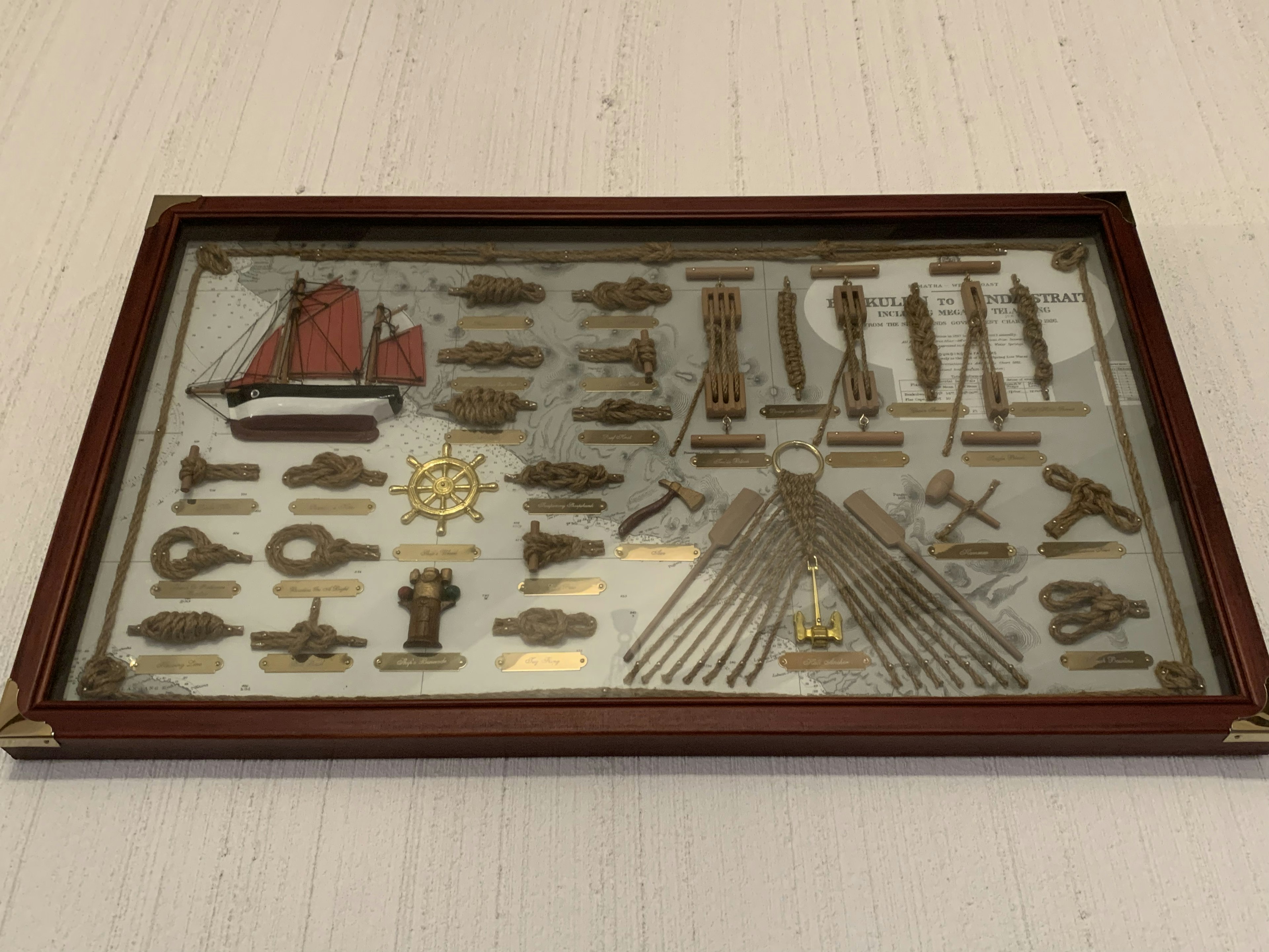 A framed display featuring various metal miniatures and tools