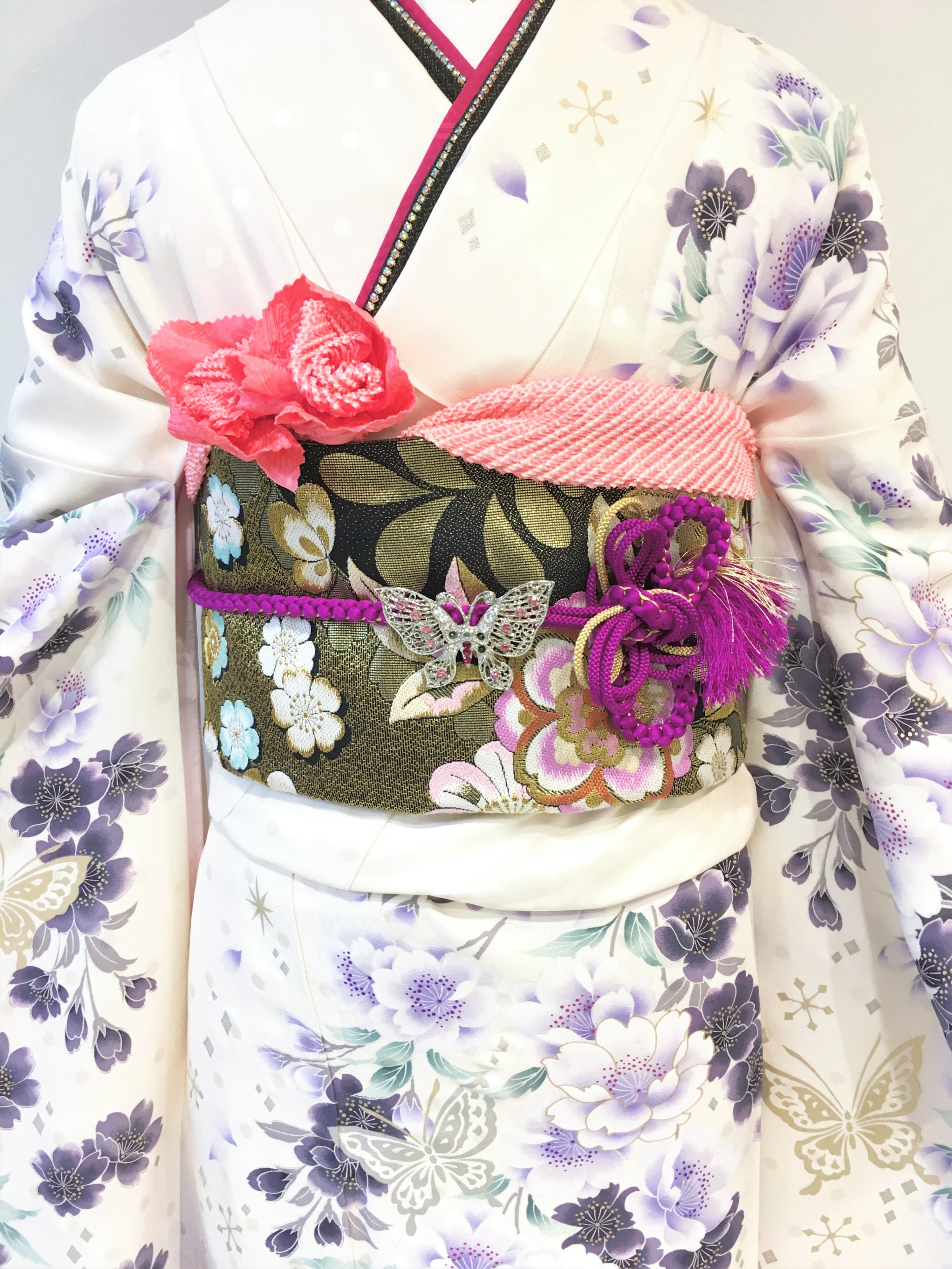 Eine Frau in einem schönen lila Blumenkimono mit einem lebhaften Obi und Blumendekorationen