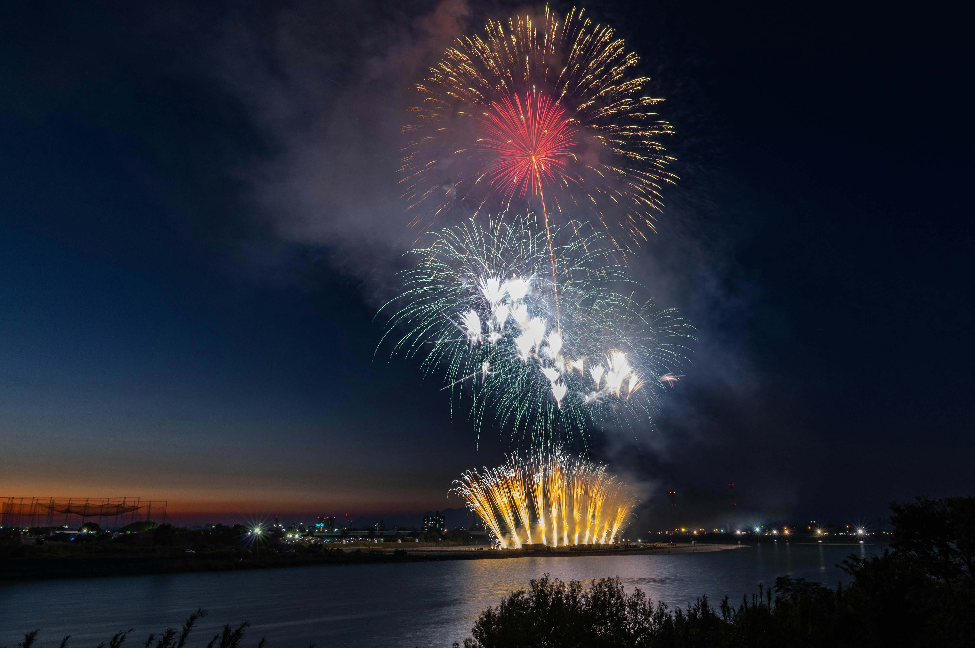 夜空に打ち上げられた花火が鮮やしく輝く川の景色