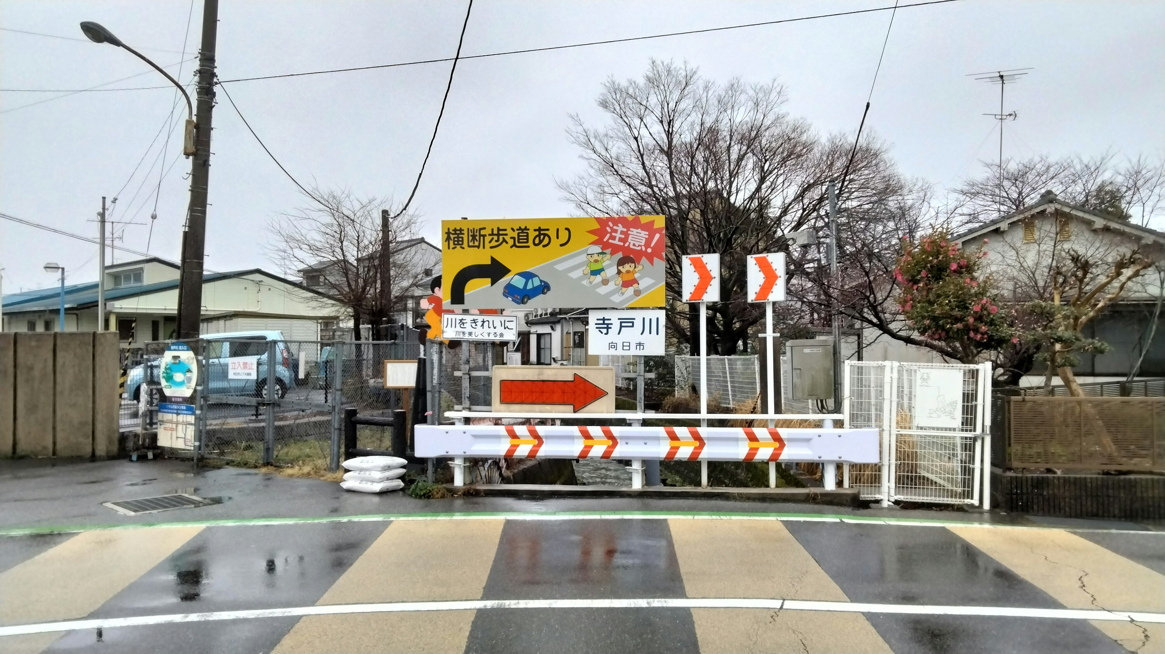 A rainy intersection featuring various traffic signs and a guideboard