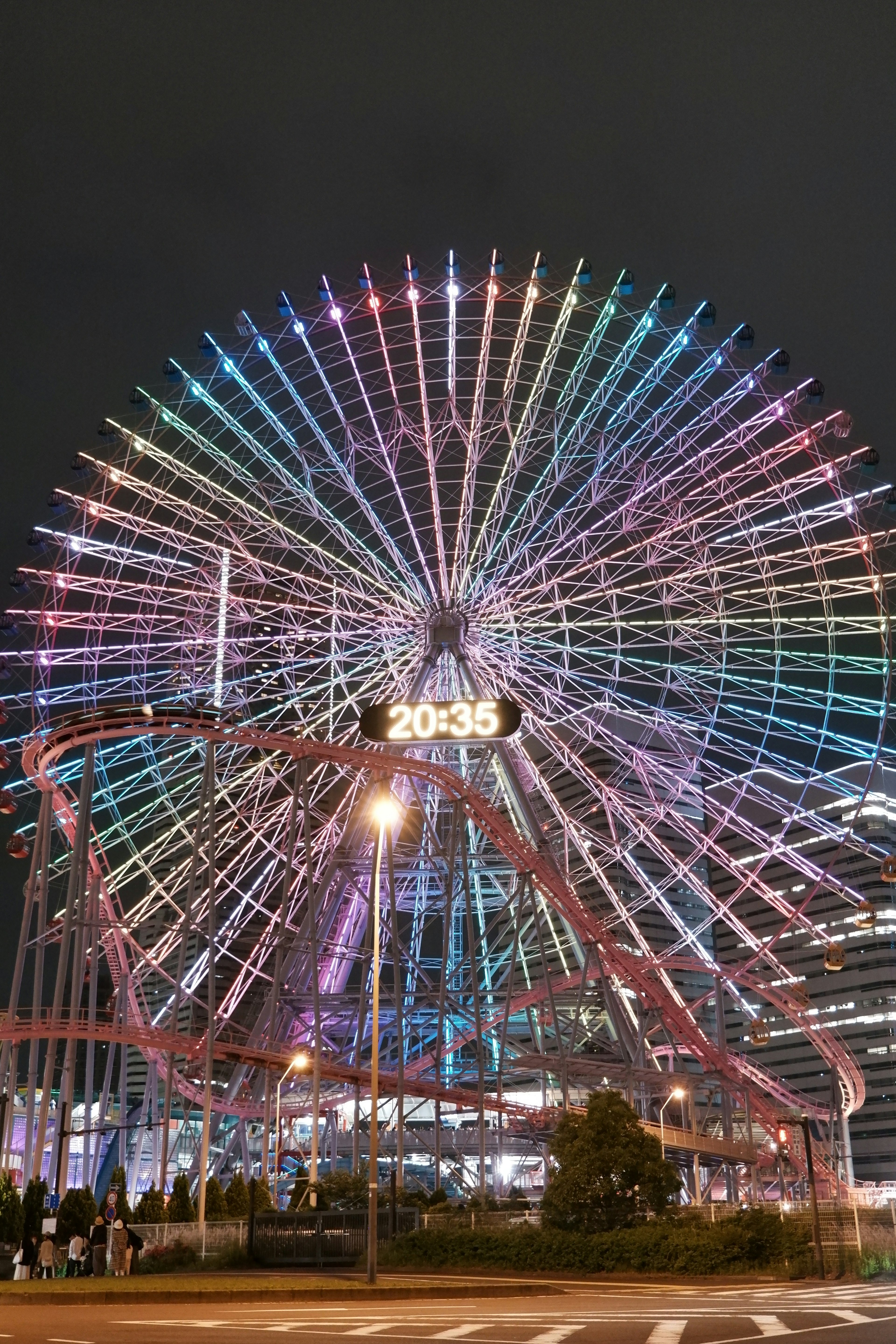 Colorful LED lights illuminate a giant Ferris wheel at night