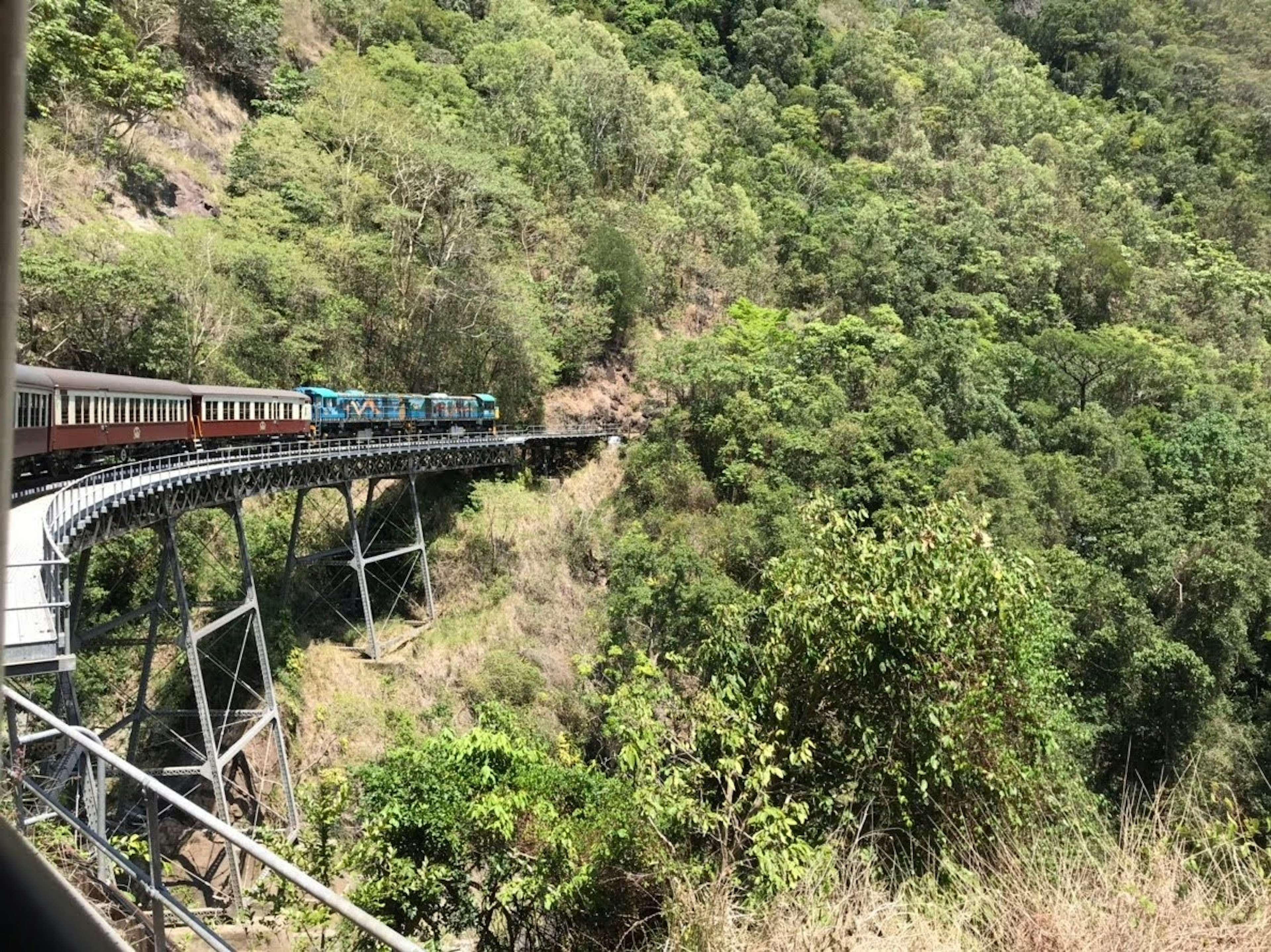 Tren cruzando un puente curvado a través de montañas verdes