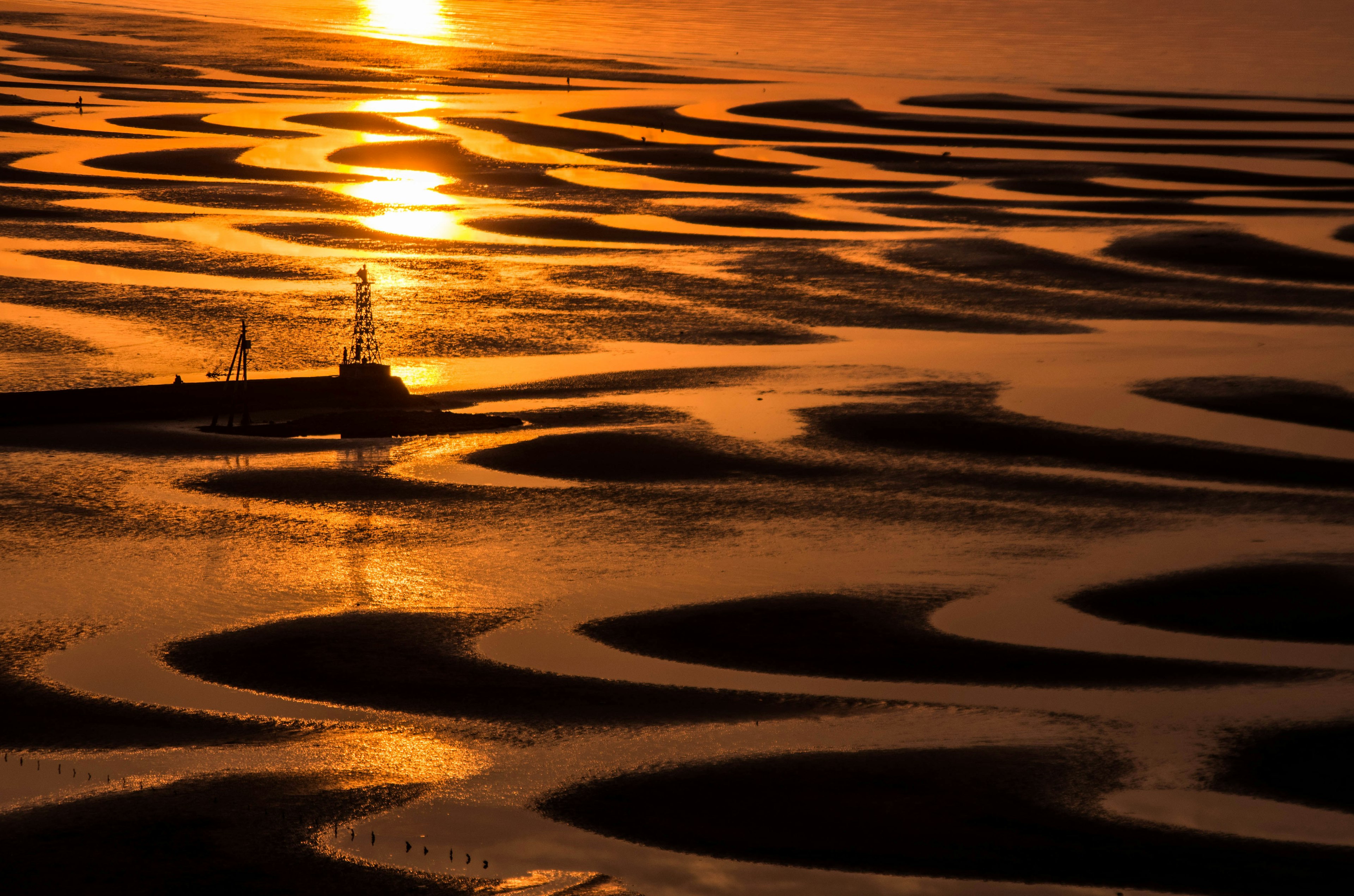 Motivi di fondali marini che riflettono il tramonto con un faro