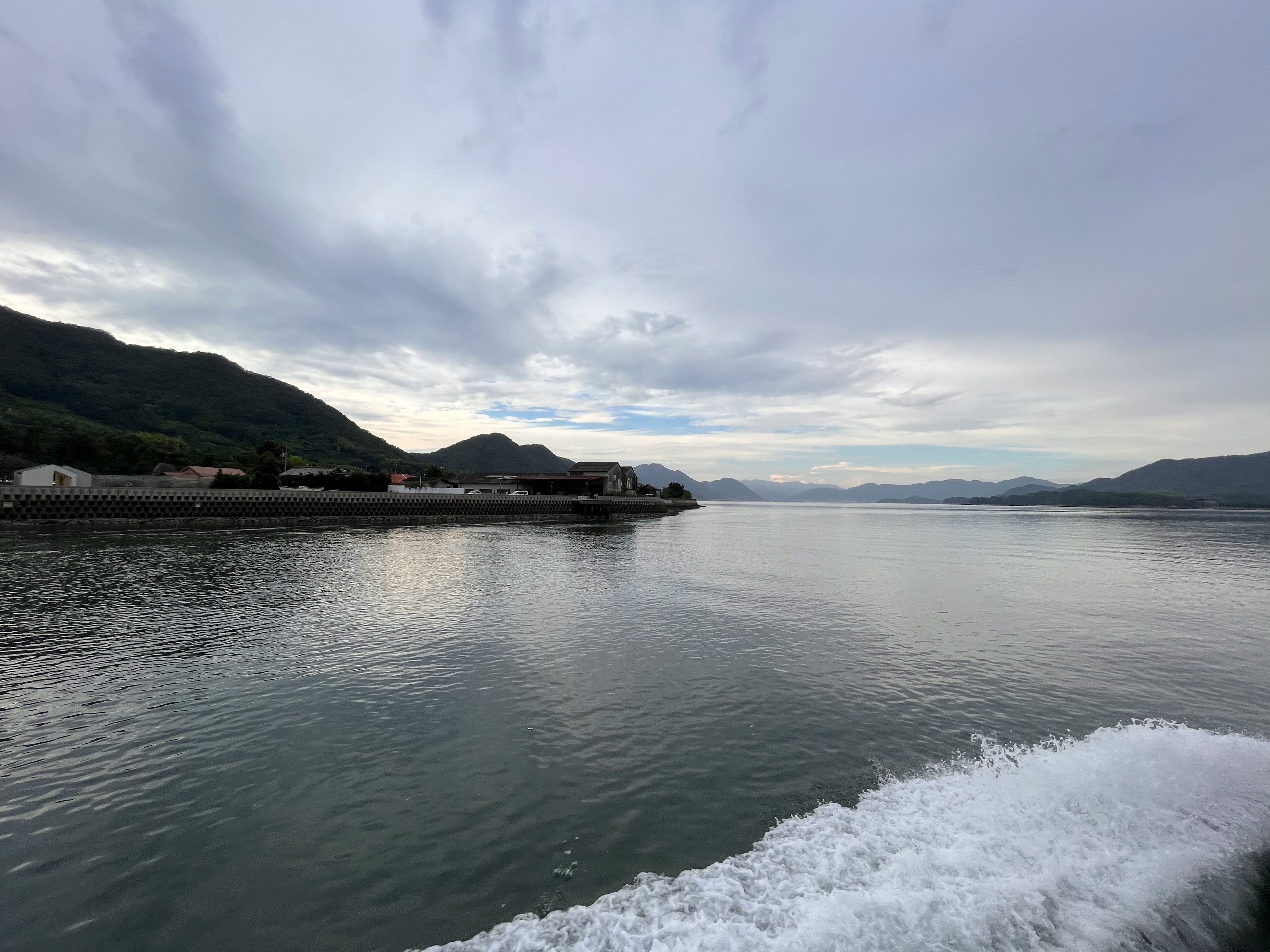 穏やかな海と山々が見える風景 船の波しぶきが映える