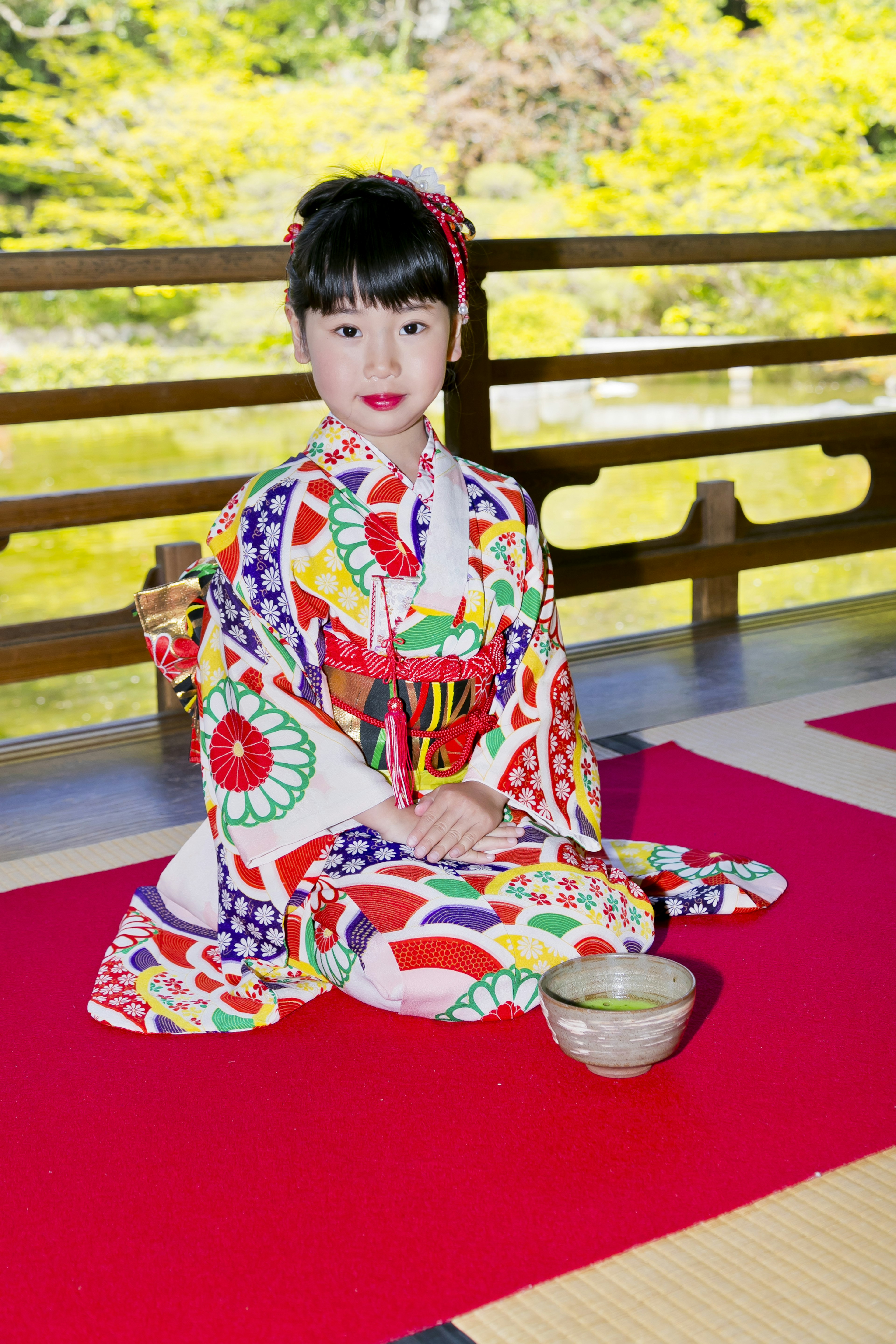 Una niña en un kimono colorido sentada en un jardín japonés