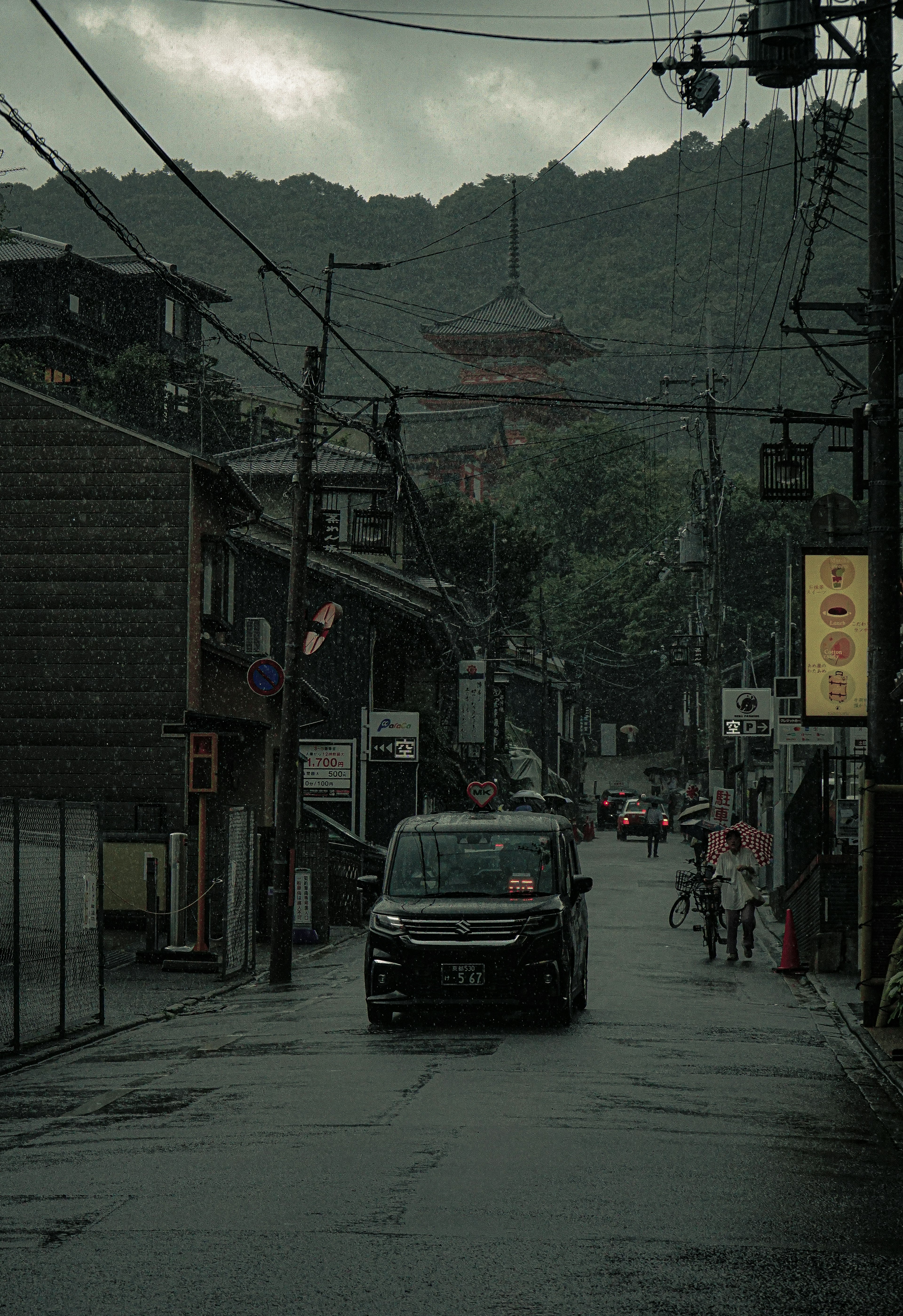 A quiet street scene with a car driving and mountains in the background