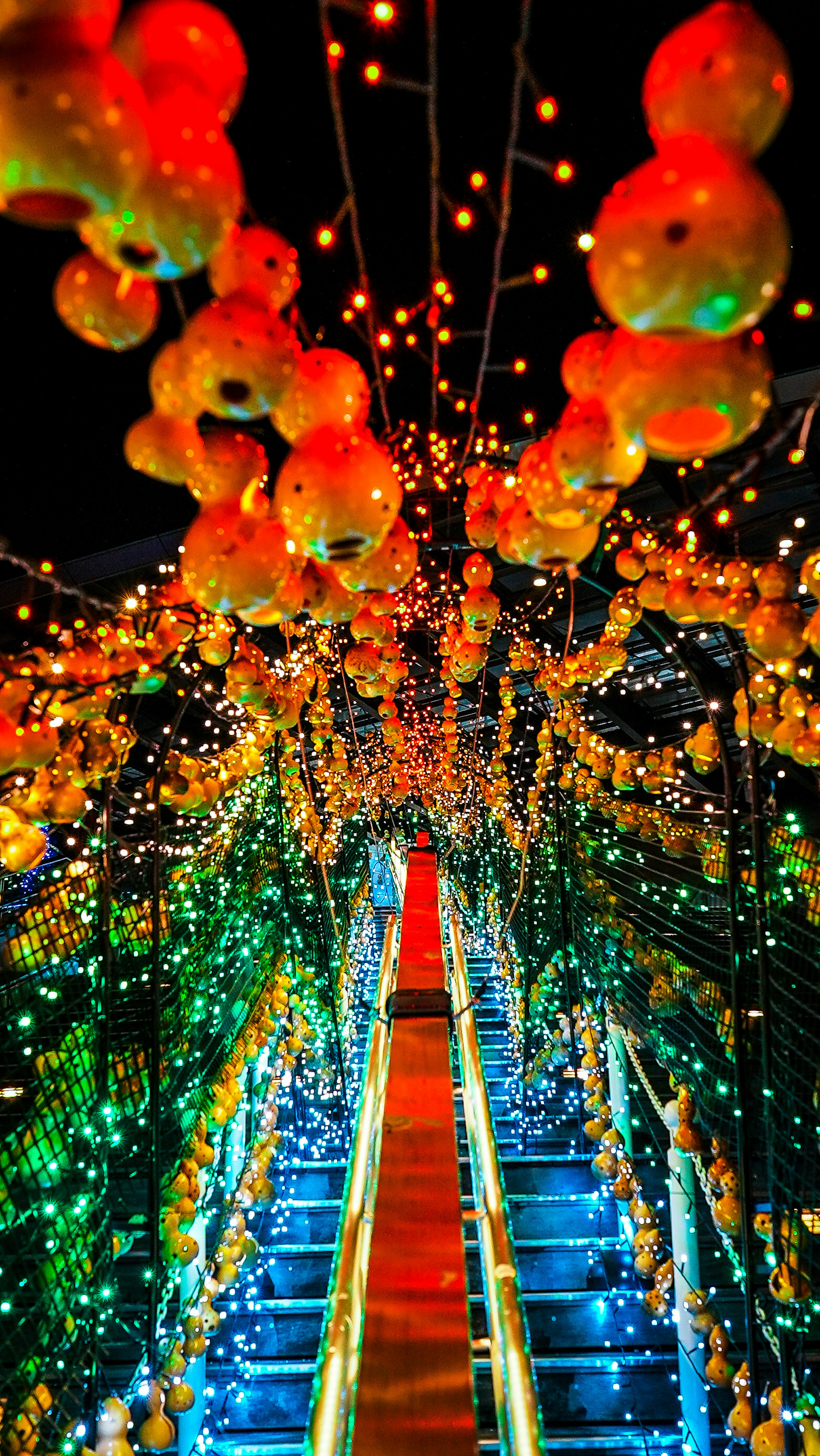 Tunnel de lanternes orange et lumières brillantes sous le ciel nocturne