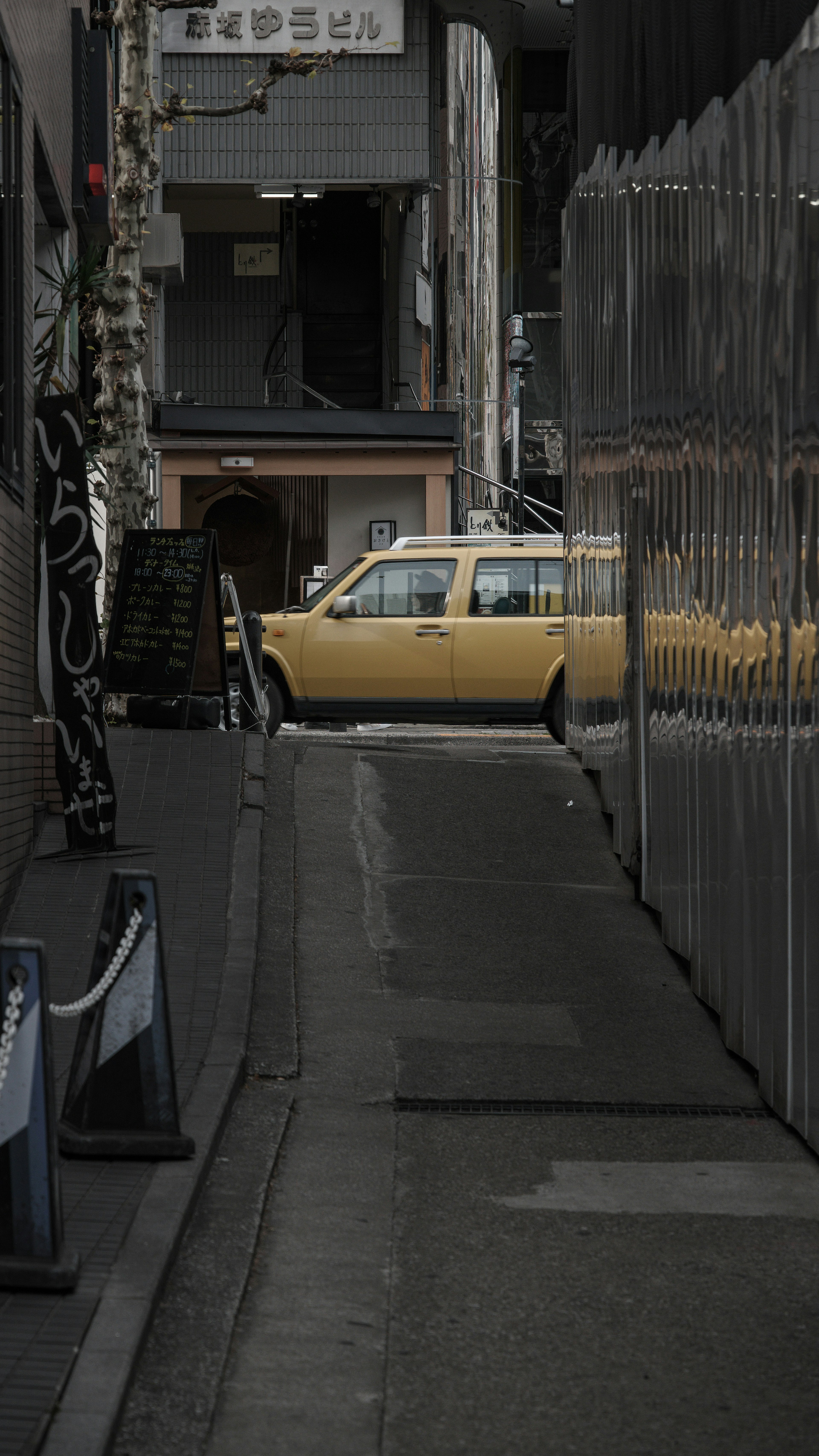 Taxi jaune garé dans une ruelle étroite avec des bâtiments environnants