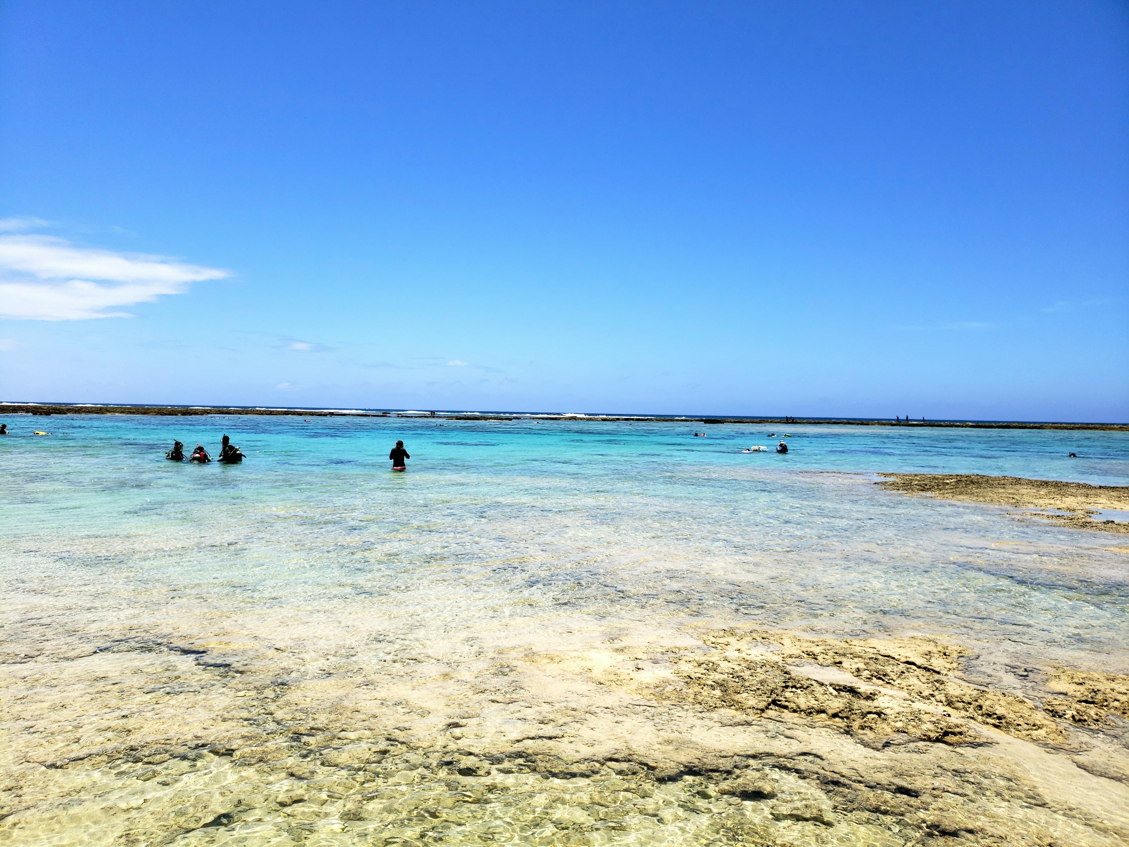 Vue panoramique d'un océan bleu clair avec des eaux peu profondes et des personnes nageant