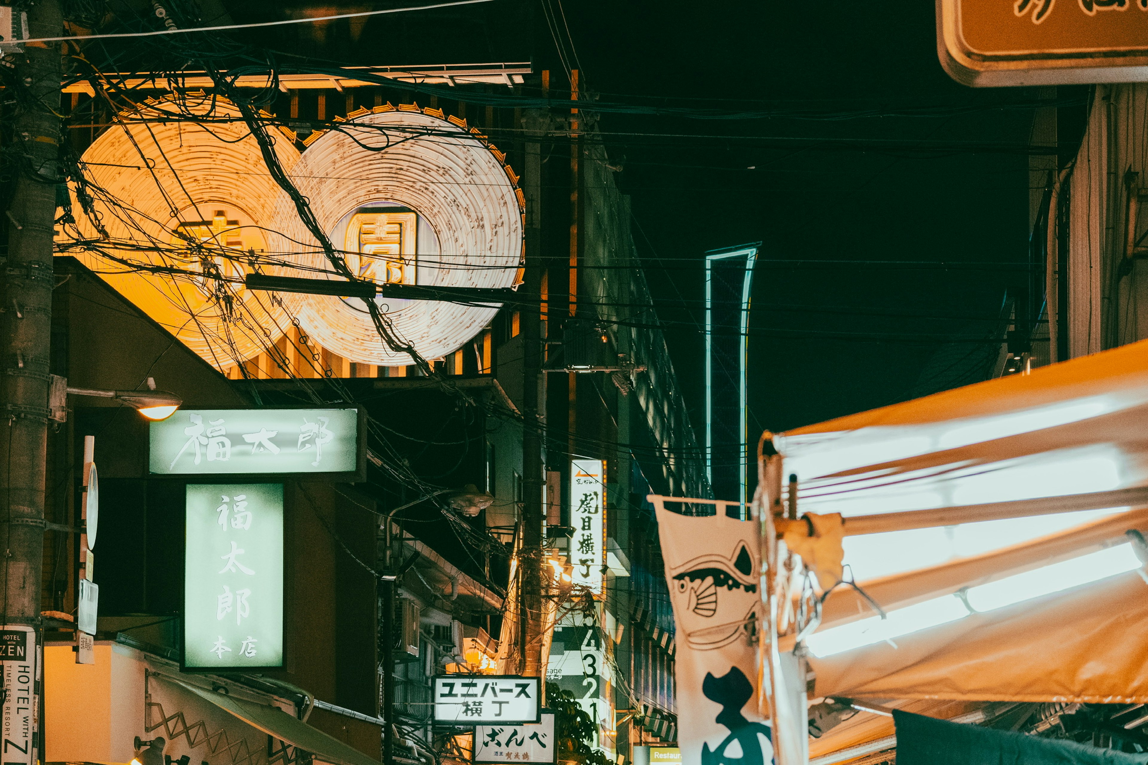 Calle de la ciudad de noche con un gran letrero y líneas eléctricas intrincadas