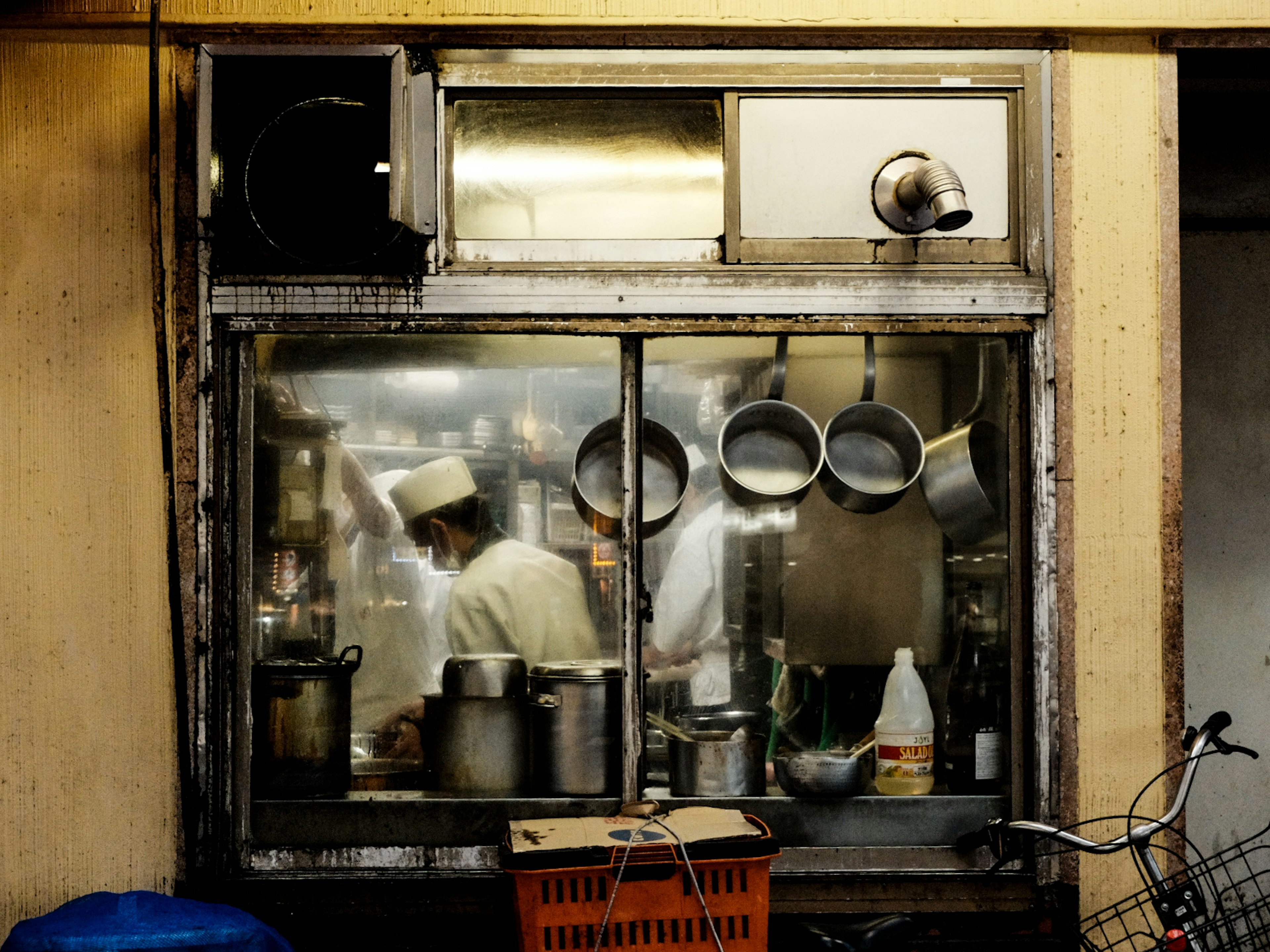 厨房の窓越しに料理をするシェフの姿が見える