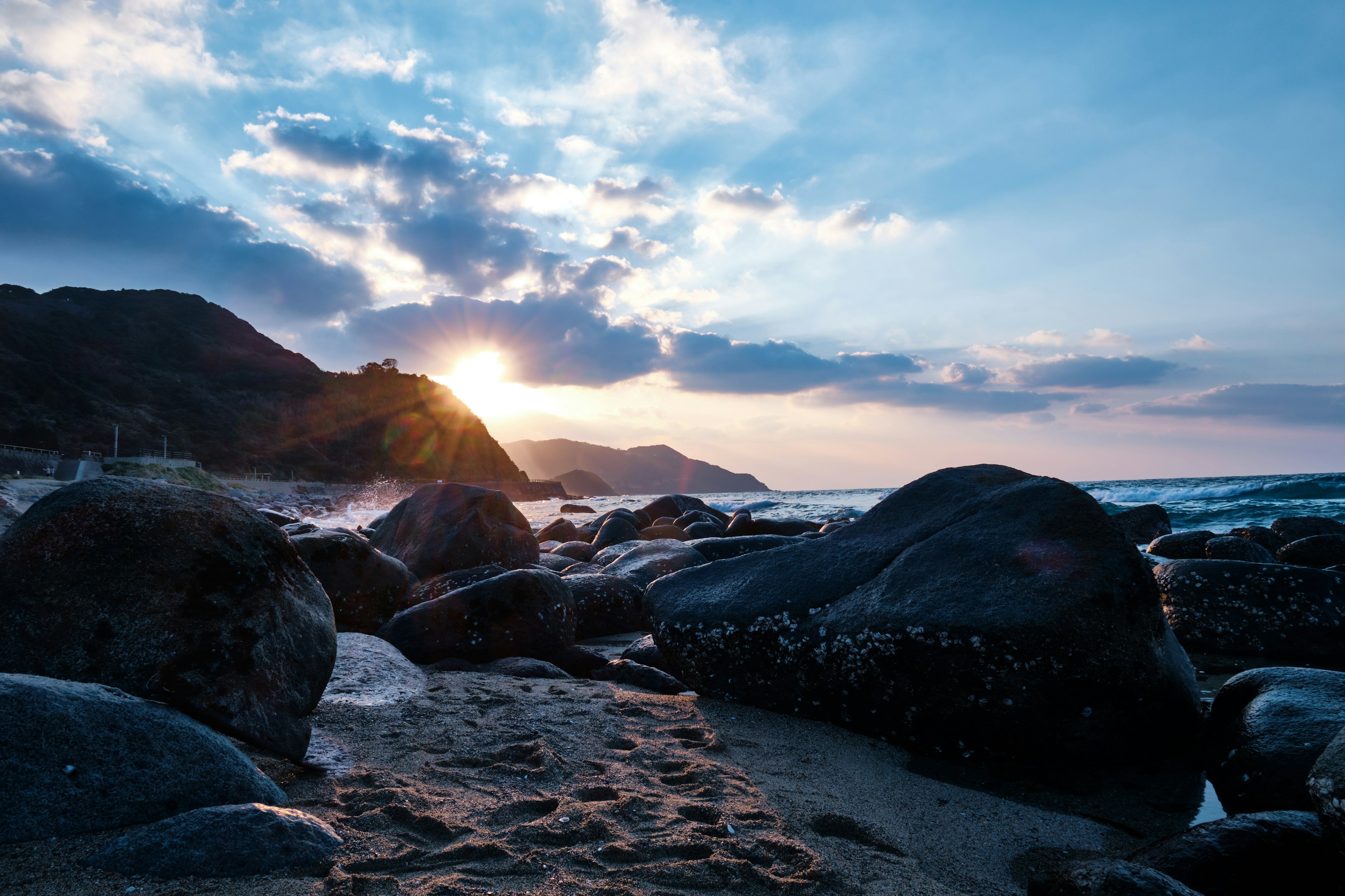 Pemandangan indah batu pantai dan matahari terbenam